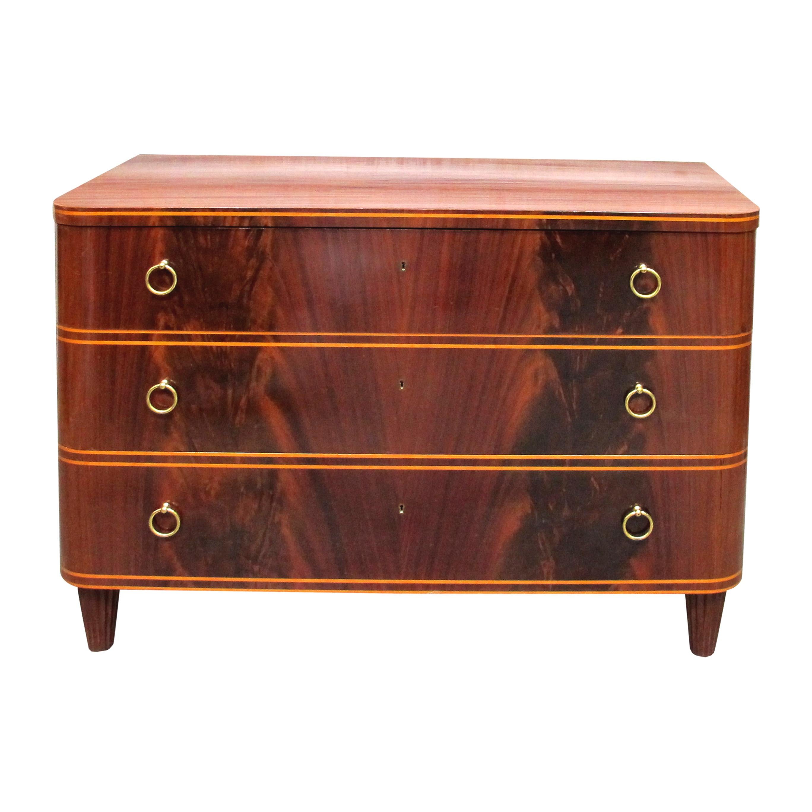 This elegant 1940s Swedish chest of drawers showcases a timeless design of mid-century Scandinavian furniture by Axel Larsson. Featuring a rich flamed mahogany wood veneer with a satin finish, the piece is accented by delicate inlaid details