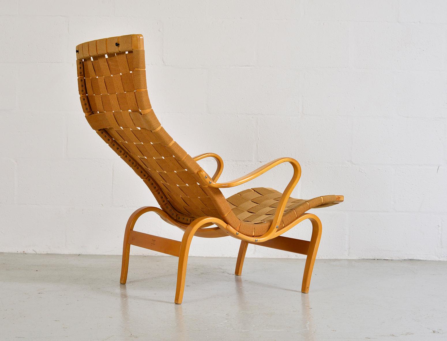 This startlingly organic easy chair model Pernilla, was designed by Bruno Mathsson and produced by Karl Mathsson AB in Värnamo, Sweden. The seating surface consists of woven webbing slung between a frame of steam-bent beech. The frame is stamped