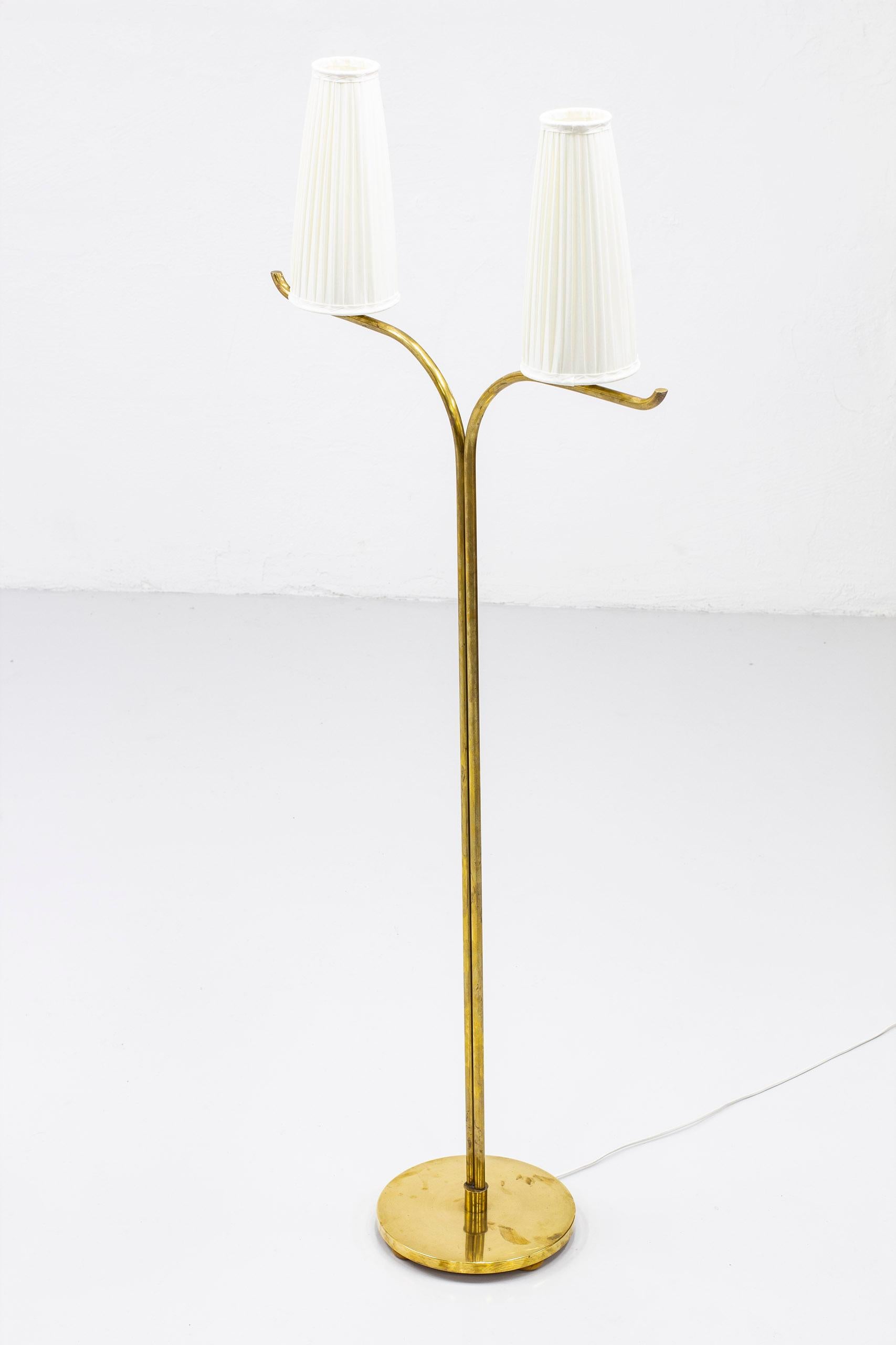Swedish modern floor lamp attributed to Gustaf Axel Berg. Produced by his own workshop in Stockholm, Sweden in the 1940s. Made from polished brass and shades with new hand sewn chintz fabric in creme white. Light switch on the chord. Very good