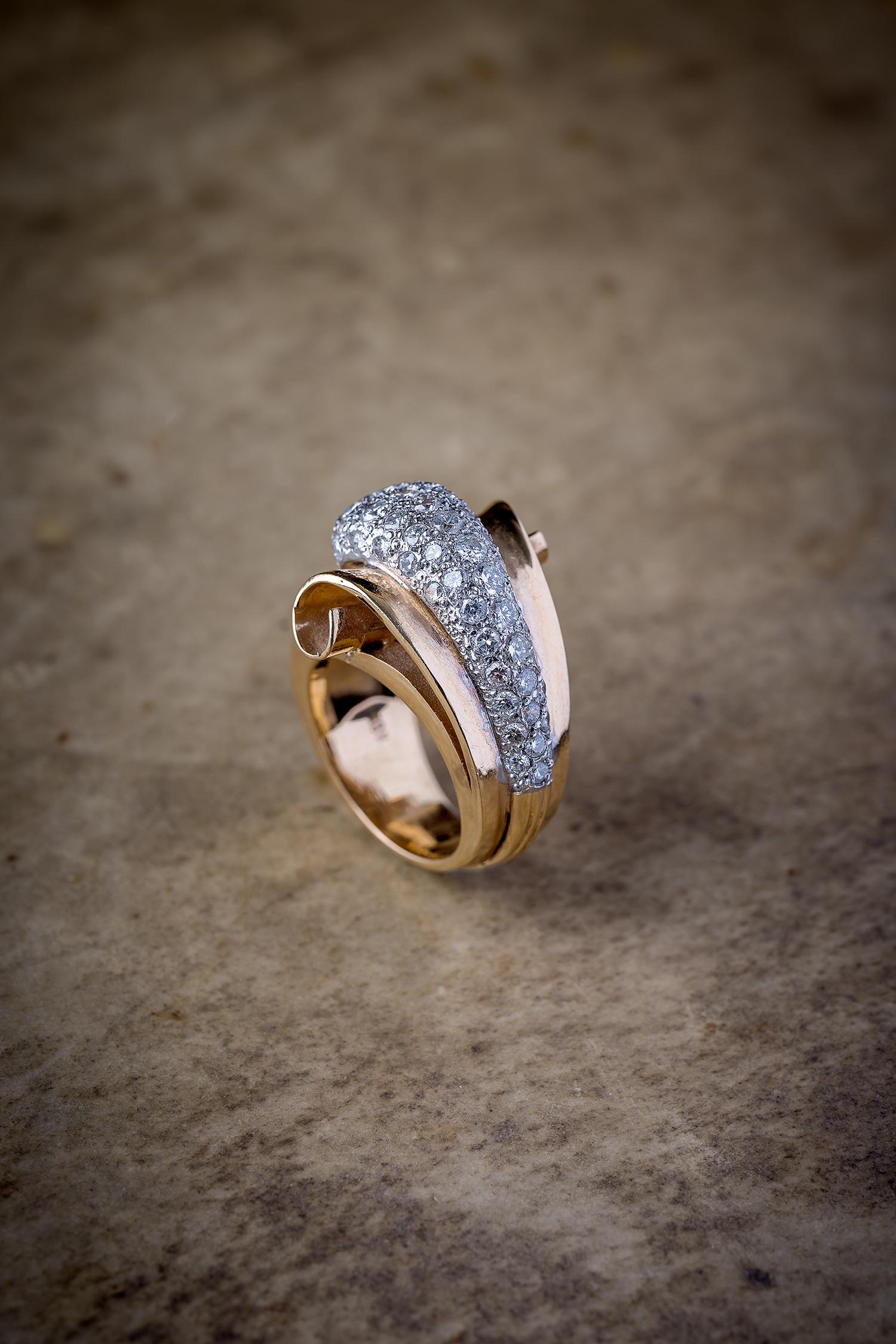 Ein großartiges Beispiel für einen wirbelnden Ring aus den 1940er Jahren, 

Gefertigt aus 18 Karat Gelbgold, mit Visier aus Platin. 
In der Mitte mit 45 Diamanten im Brillantschliff besetzt, insgesamt ca. 1,7ctw. 

8,4 Gramm Größe 6. 
20 mm breit,