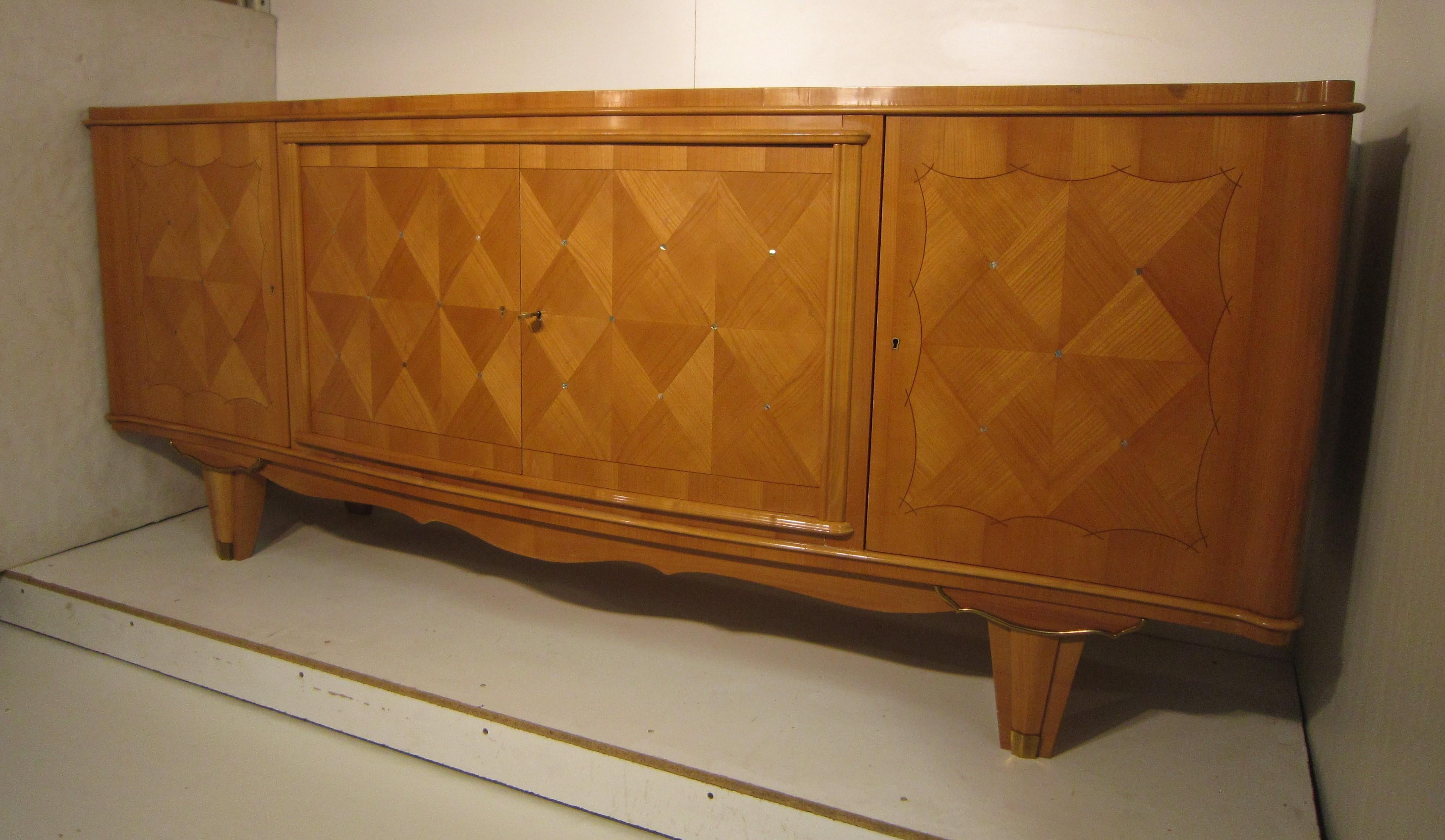 Elegant French midcentury sycamore sideboard attributed to Andre Arbus, showcasing four exquisite geometric patterned parquetry and marquetry blonde wood doors inlaid with mother of pearl dots.
The central doors feature a molded surround.
All