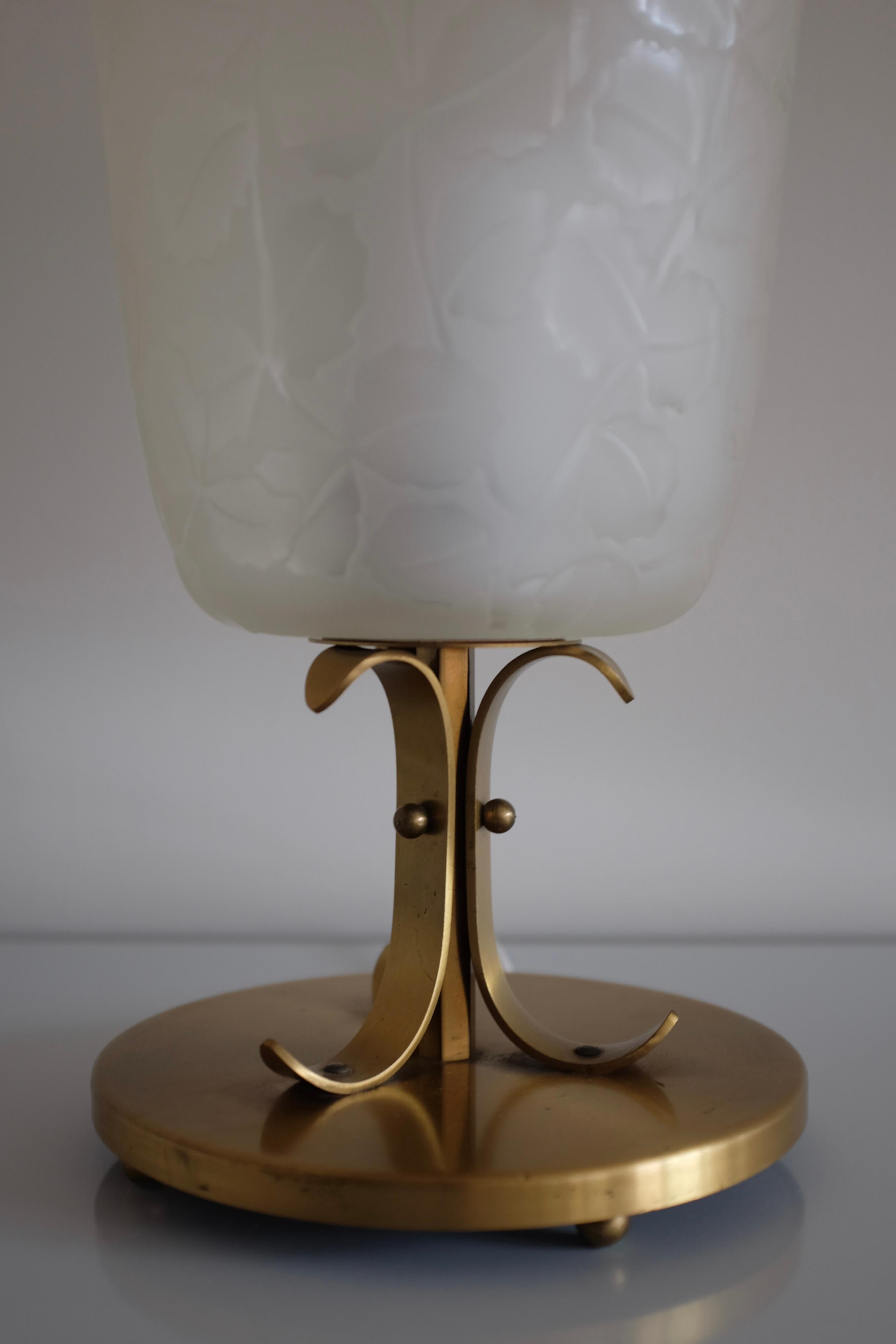 Seltene Tischlampe von Glössner & Co. aus den 1940er Jahren, Schweden. Wunderschön gravierte Blätter bedecken die Glaslaterne, die auf einem Lampenfuß aus Messing mit dekorativen geschwungenen Ornamenten steht. Glössner & Co war ein schwedischer
