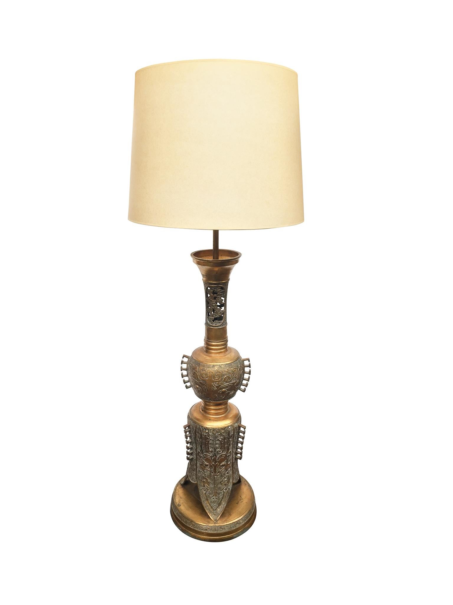This 1940s table lamp is comprised of a gold-hued brass candelabra body with intricate embossed and incised patterns. The style and use of a traditional candlestick form as a table lamp are reminiscent of the extravagant, but nevertheless stunning,