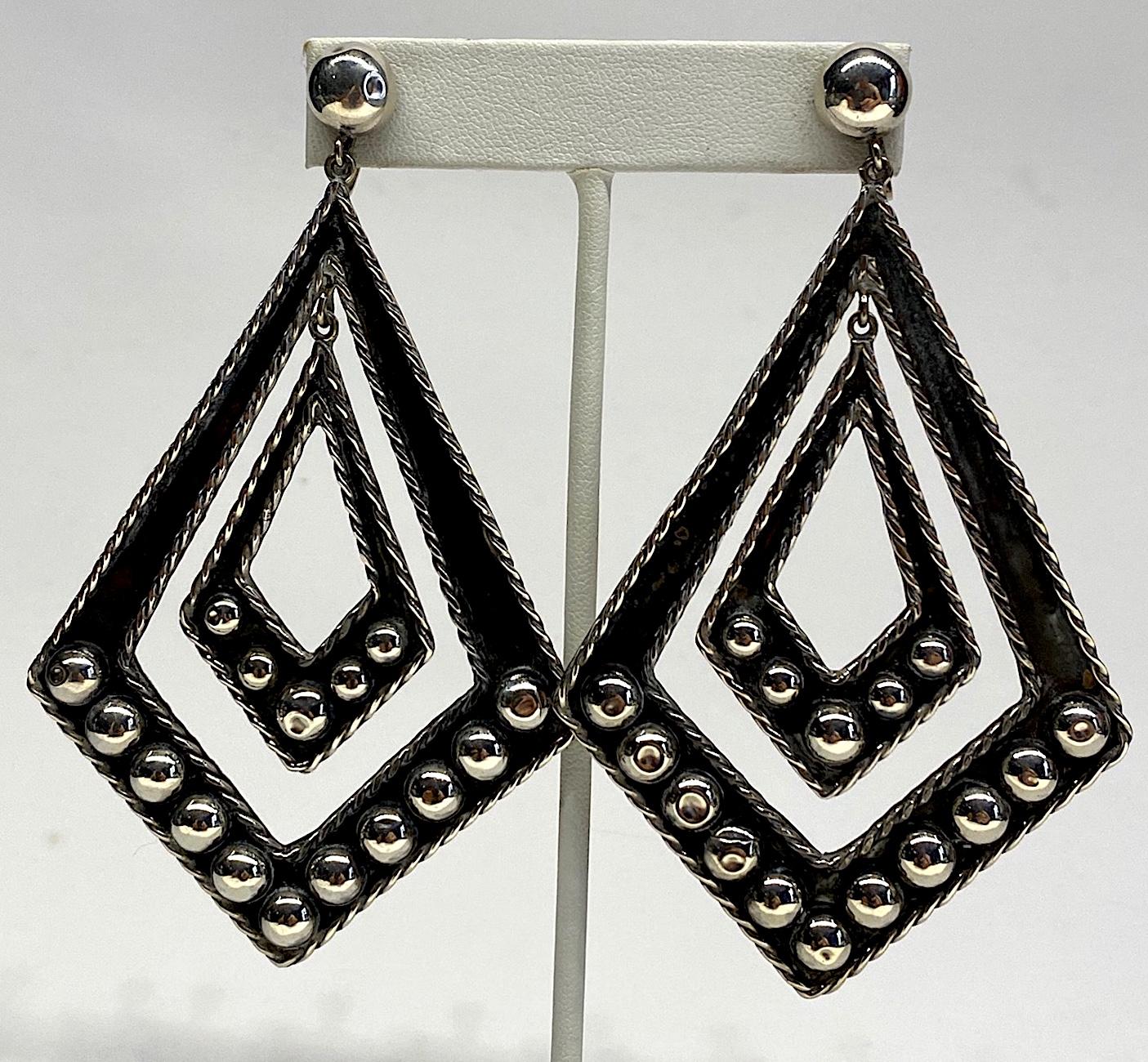 A beautiful pair of artisan made late 1940s to 1950s sterling earring from Taxco, Mexico. Each earring is 2.5 inches wide and 4 inches long with a screw back typical of the period. The larger diamond houses a smaller 1.13 wide and 2 inch long