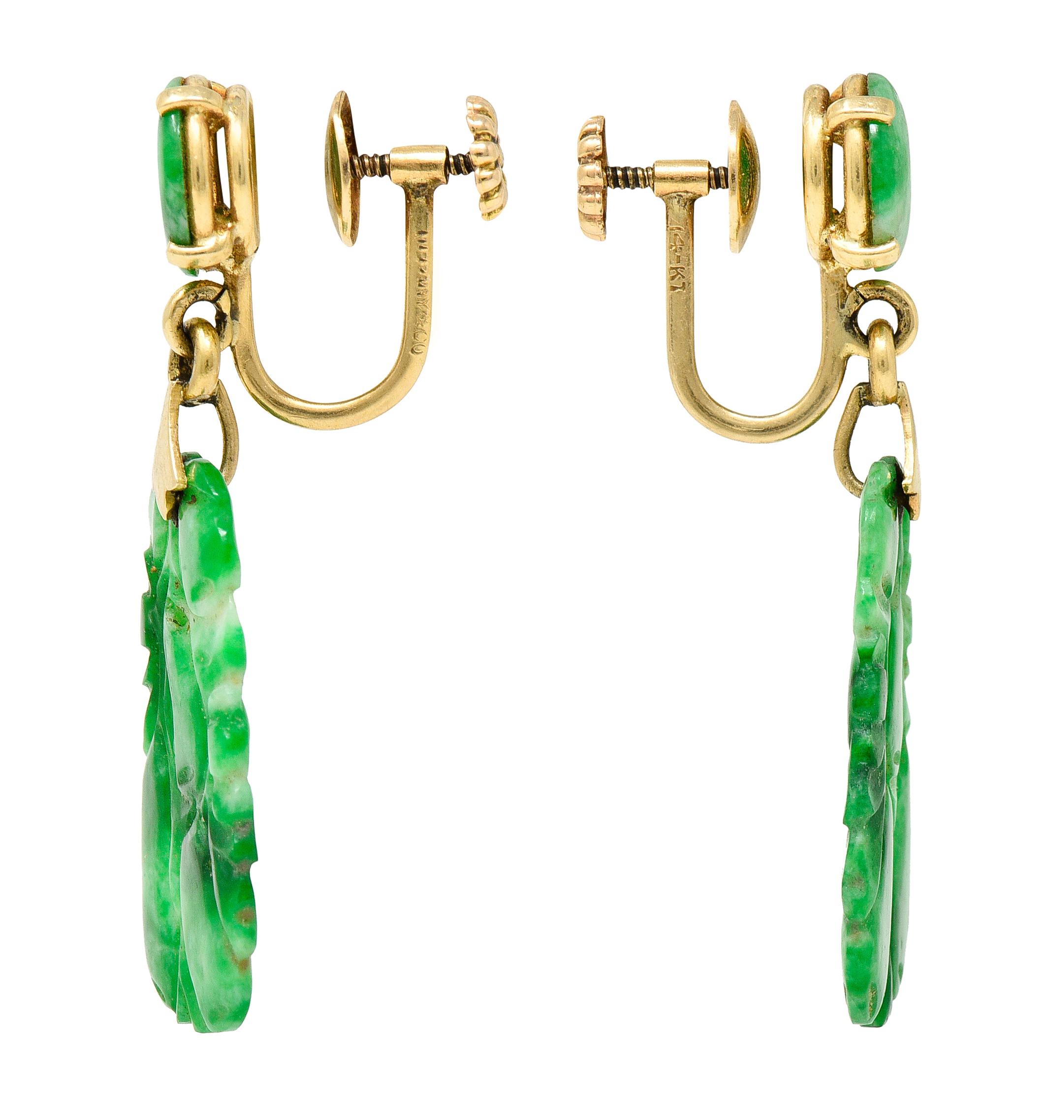 Screwback earrings surmount is a basket set 8.3 mm jade cabochon button. Suspending an articulated tablet jade drop with a stylized yellow gold foliate bale. Drop is carved to depict fruit nested in tree branches. Overall jade is opaque with strong