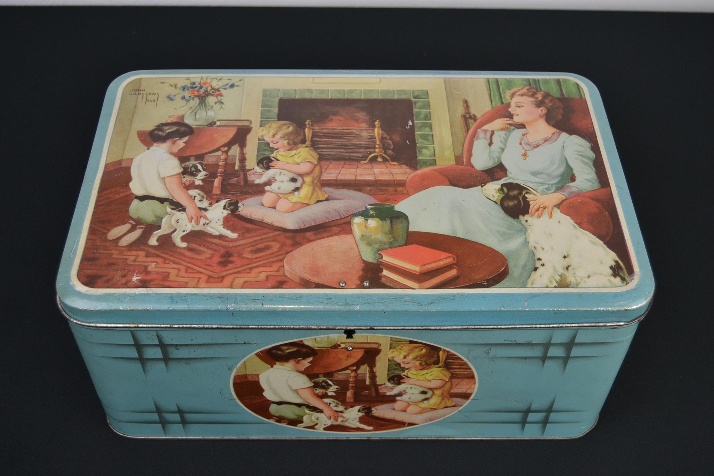 Vintage tin with dogs and children from the late 1940s.
This beautiful tin box was designed by John Janssens in 1948. 
It's a tin storage box with a beautiful design: 
Light blue tin with lid, children playing with the puppy dogs while the mother