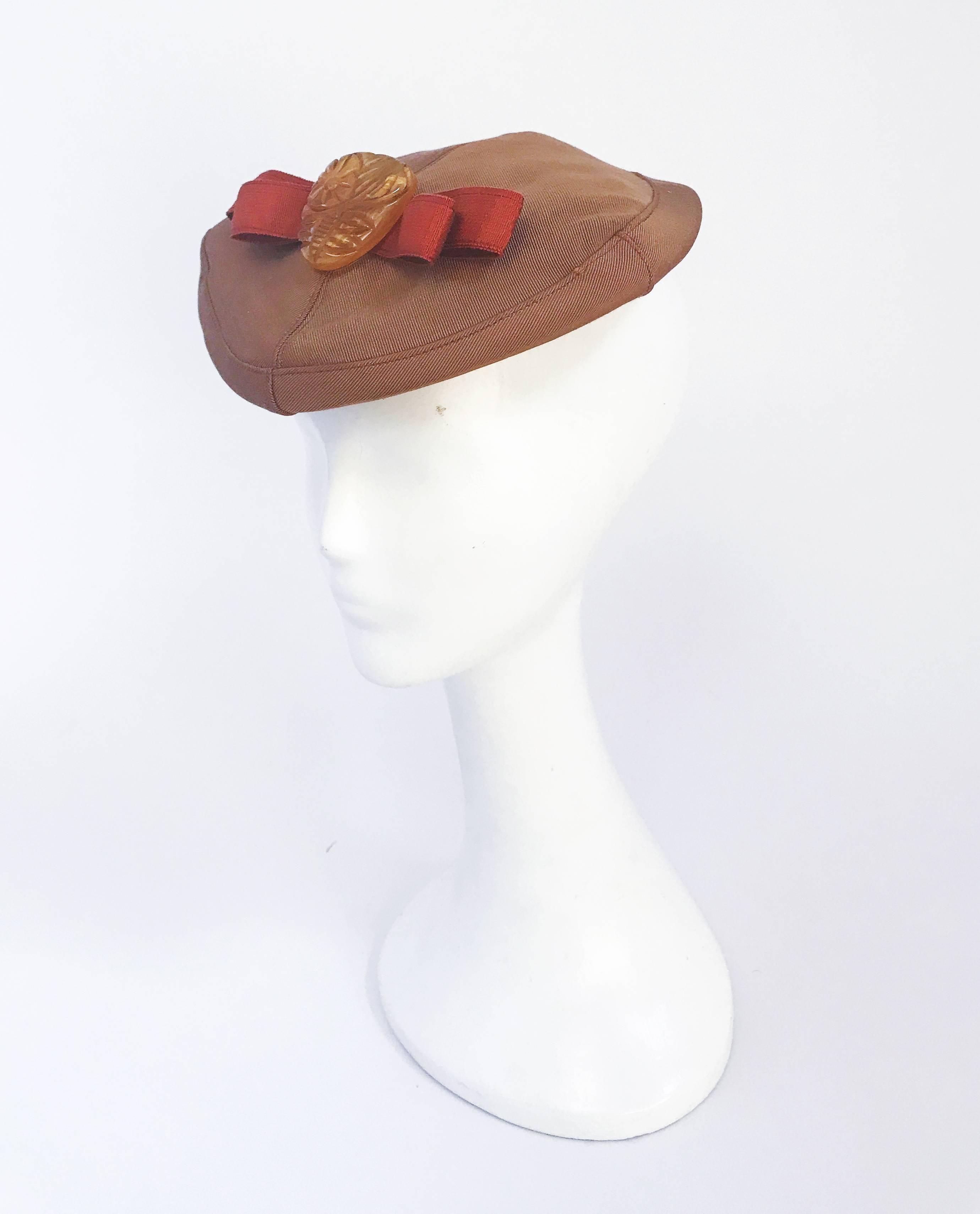 Cappello anni '40 in twill dorato con nastro Gros-grain color ruggine e fermaglio in bachelite. Dimensioni aperte.