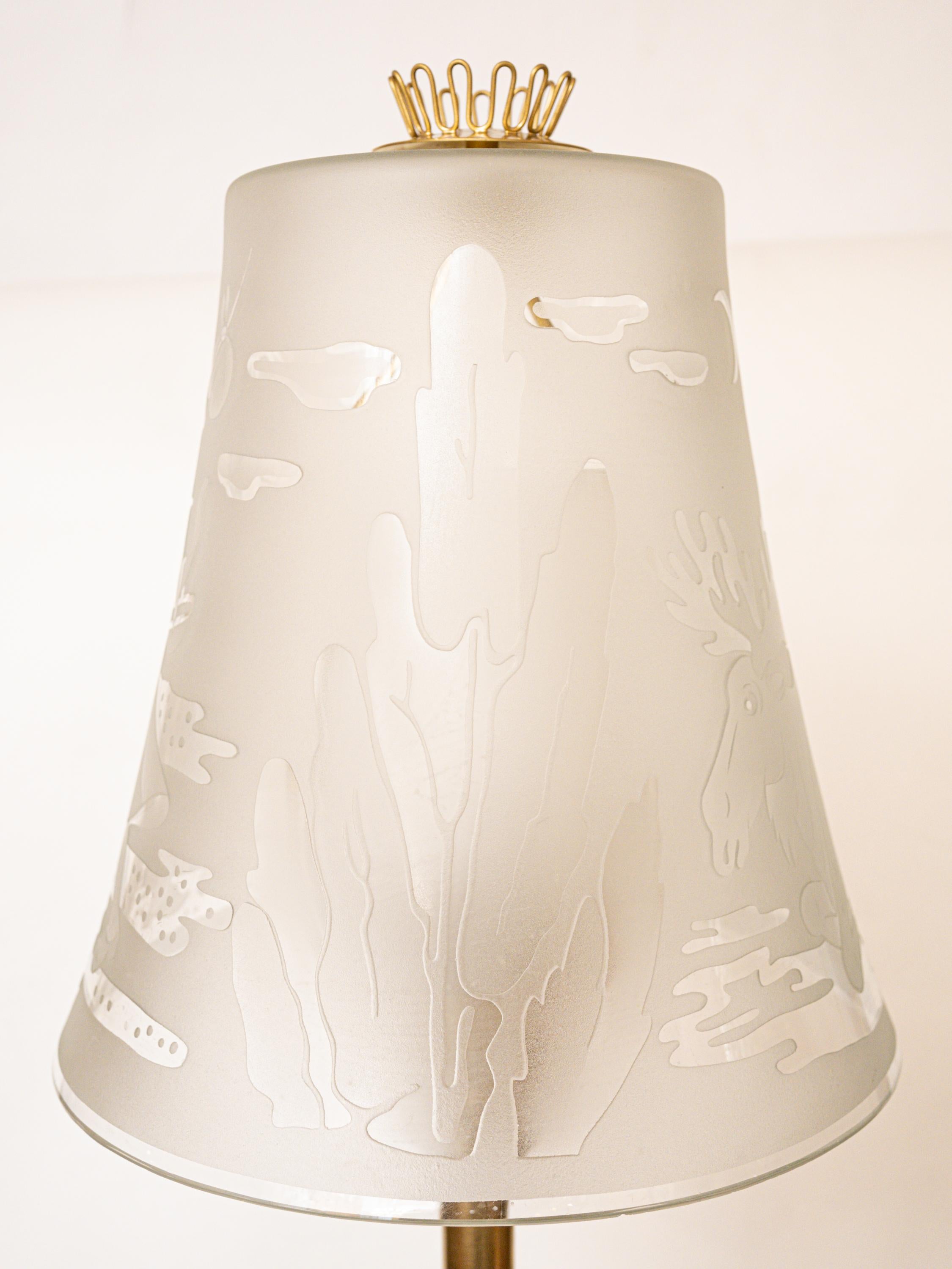 A glass shade lamp by Swedish designer Ulla Skogh, having an intricate designed sandblasted glass shade with depictions of women in folk clothing and forest wildlife. Signed Glossner-Co- U. Sogh. Circa 1940s.

Overall Height: 68.5