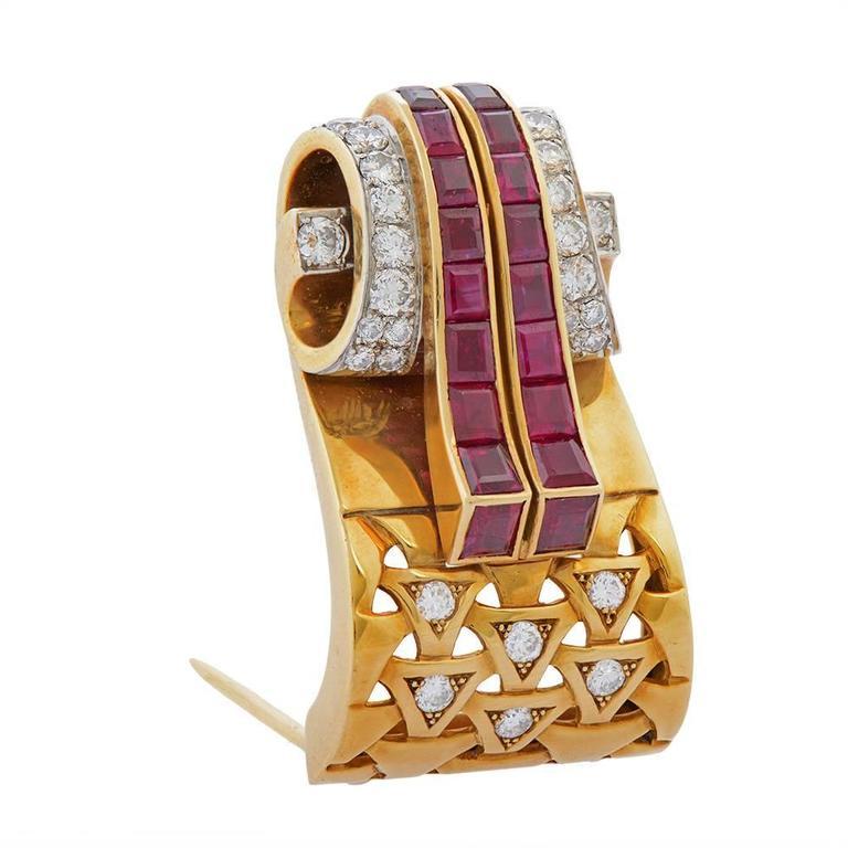 A gold, diamond and ruby brooch by Van Cleef & Arpels, of three-dimensional scroll design, the gold ribbons of channel-set, square- and baguette-cut rubies flowing over the scroll pavé-set with round brilliant-cut diamonds and diamond-accented