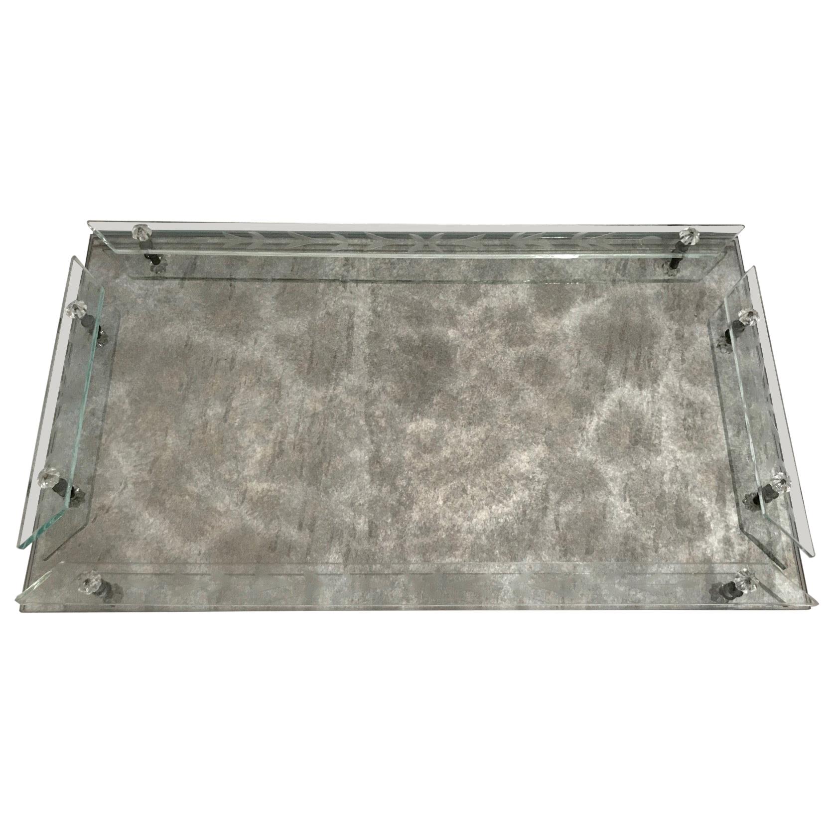 Hollywood Regency and Art Deco era Venetian mirrored tray with smokey grey antique cast and veining. The vanity tray is fitted with art glass gallery rails featuring elegant hand etched floral designs, and features glass rosette accents. Perfect for