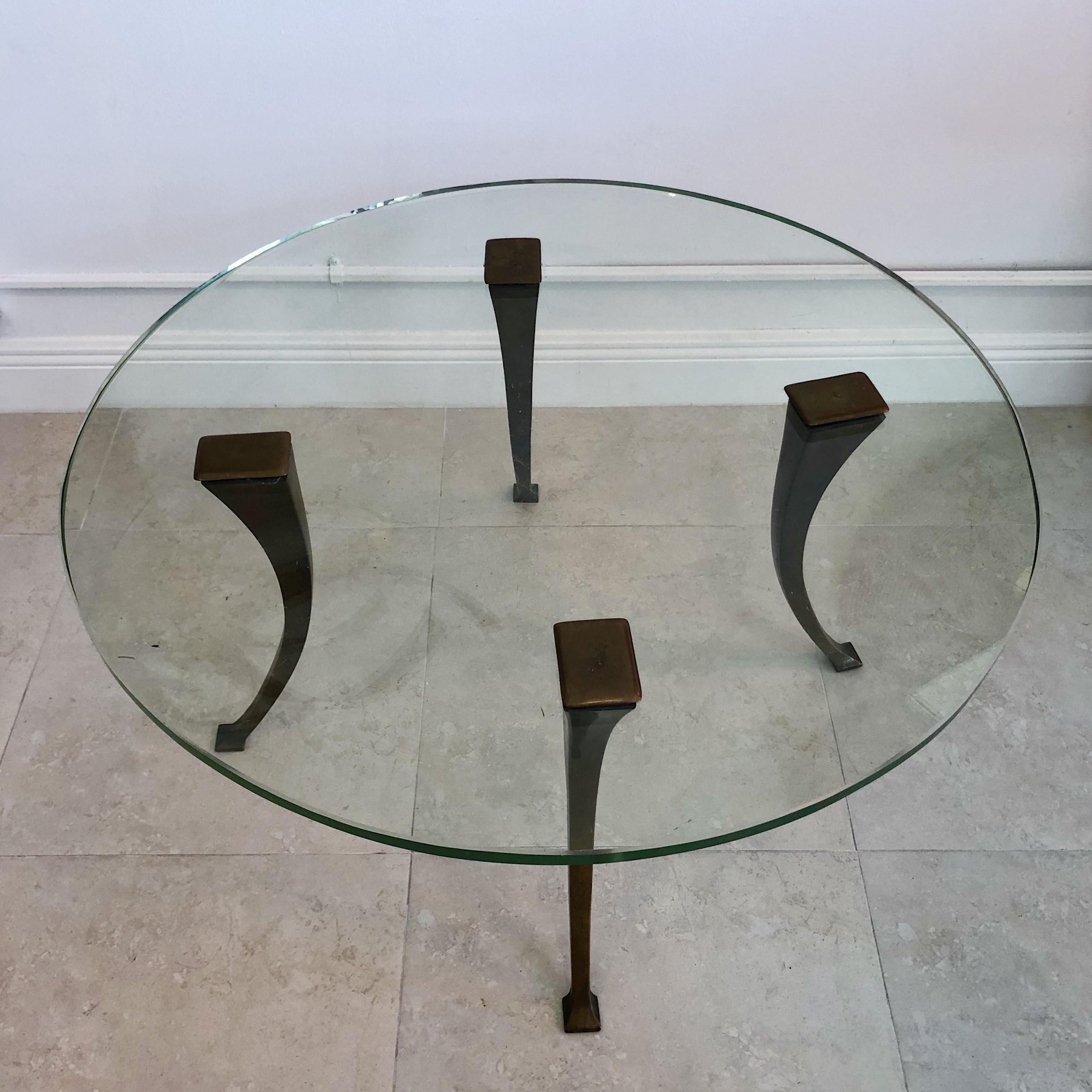 This is an exceptional coffee table that is sure to add a touch of elegance and sophistication to any living space. The table features four patinated bronze legs that have a beautiful, natural patina. The original 1940s glass top is the centerpiece
