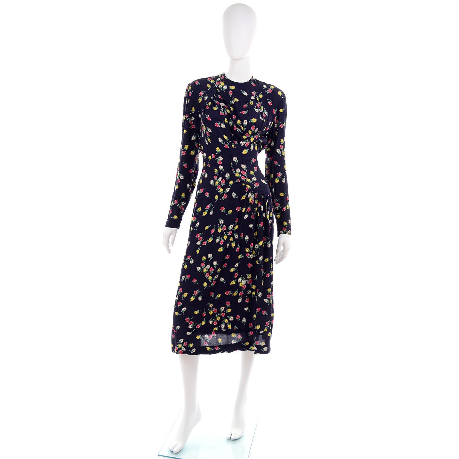 This is a great 1940;s  vintage navy midi dress with a colorful rosebud print. The pretty roses are in shades of pink, yellow and white with green stems. This dress is easy to assimilate into a modern wardrobe and has long sleeves, a gathered 