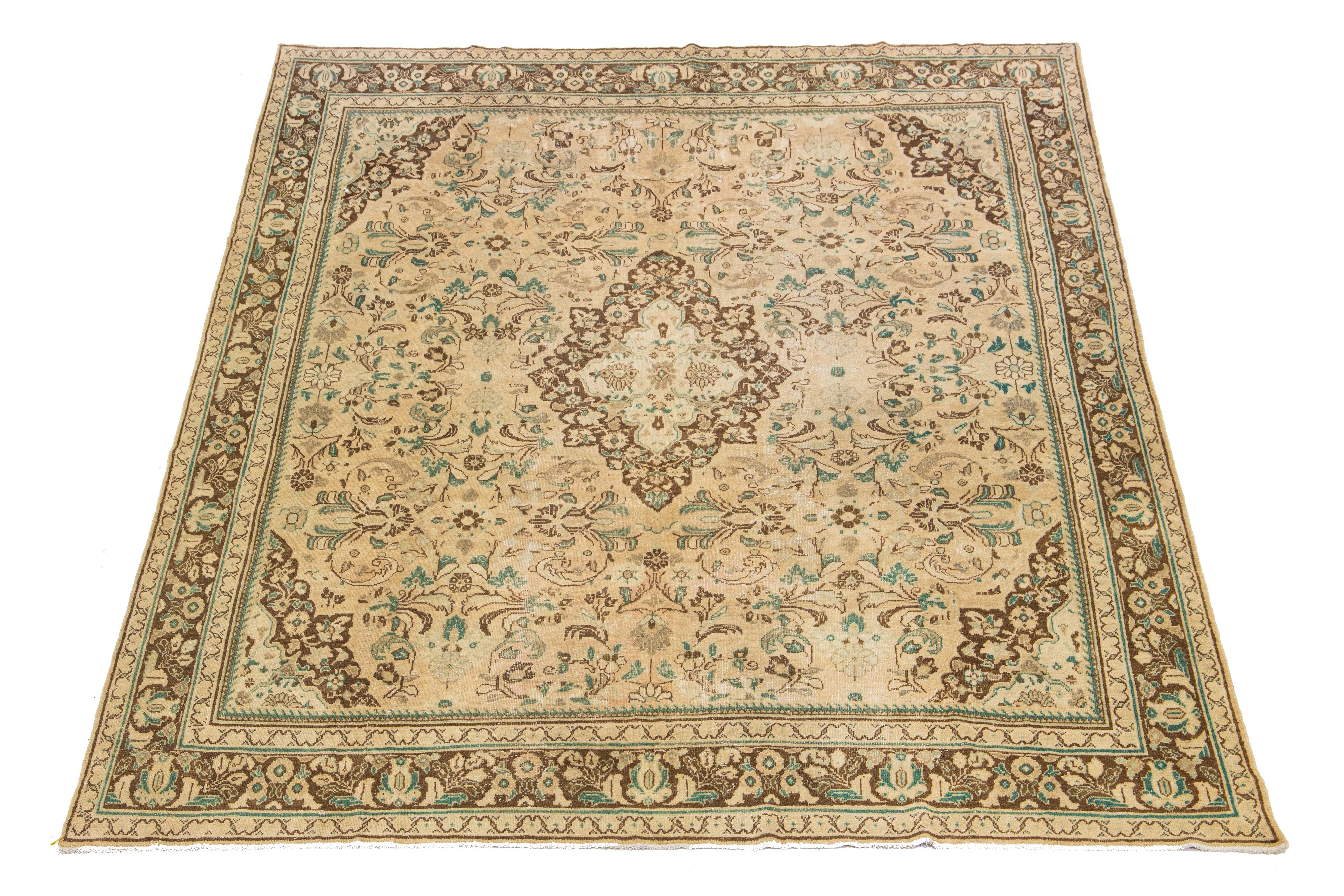 Beautiful Vintage Mahal hand-knotted wool rug with a tan color field. This Persian rug has classic green and brown hues throughout the floral motif.

This rug measures 10'5