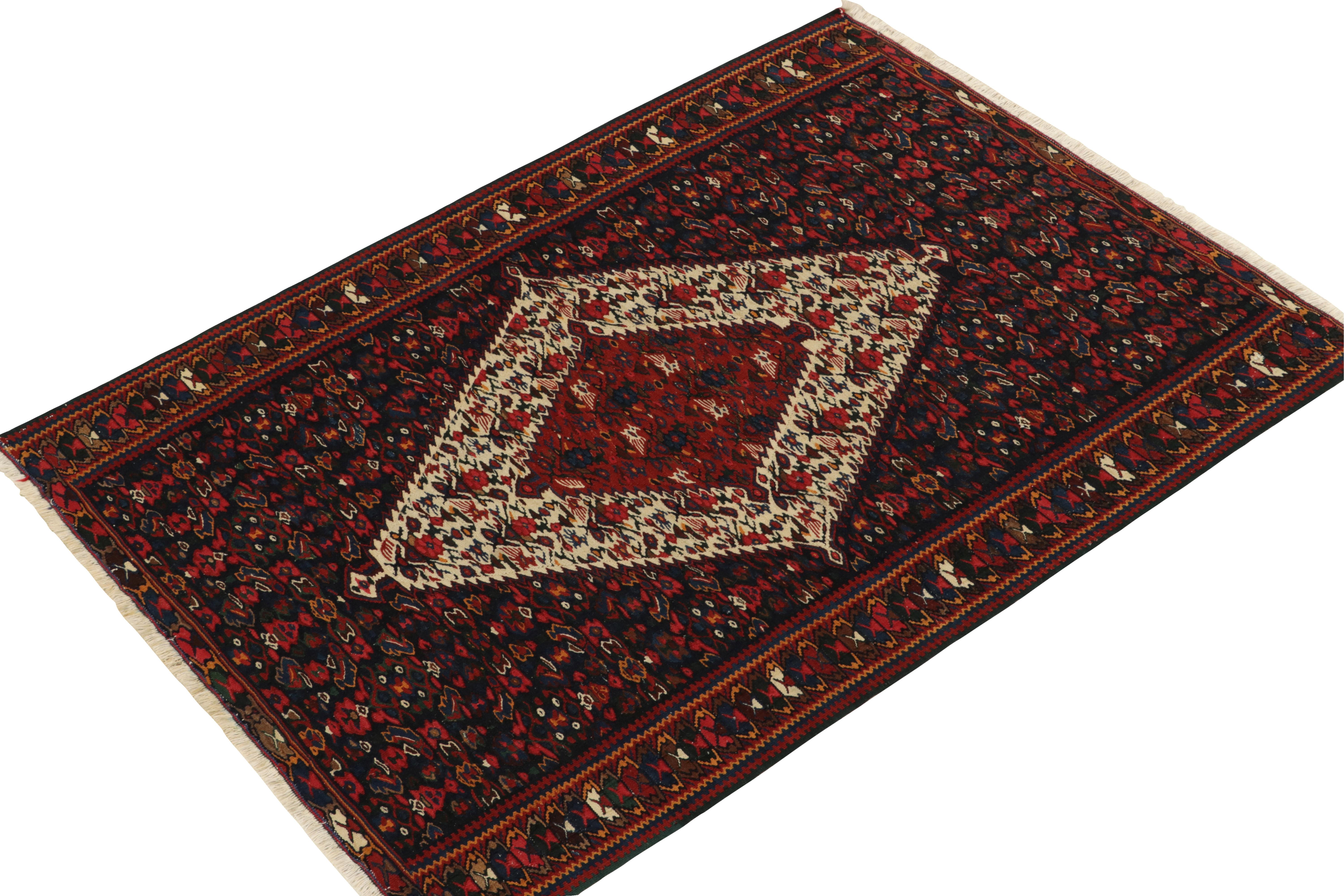Hailing from Persia circa 1940s, a mid-century kilim rug newly unveiled Rug & Kilim’s vintage selections. The Senneh kilim rug connotes a union of  medallion and all-over field patterns with a rich array of burgundy red, deep blue and prevailing