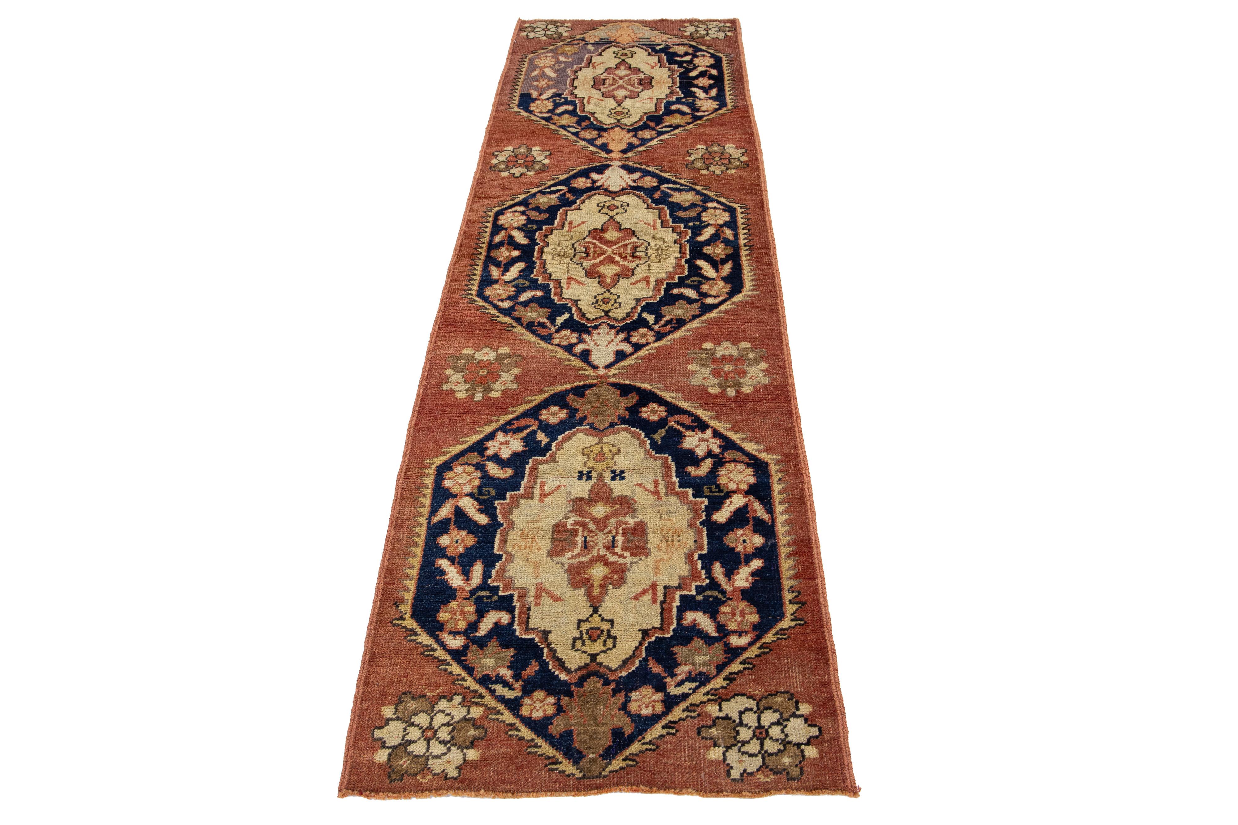 Magnifique tapis de course turc vintage présentant un champ rouge-rouille décoré d'un motif tribal traditionnel en médaillon qui s'étend sur l'ensemble du tapis, mis en valeur par des teintes bleu marine, beige et marron.

Ce tapis mesure 2'6