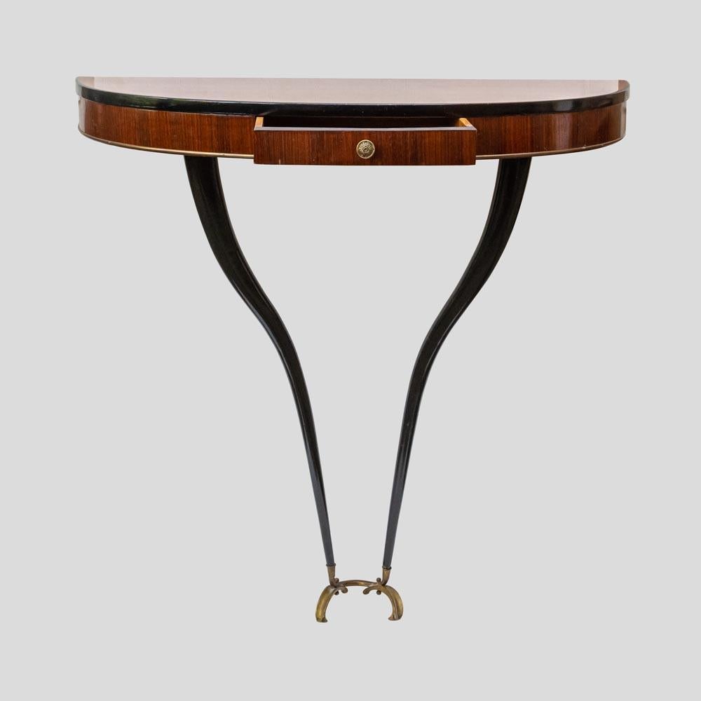 Original 1940s Half Moon shaped wall mount Console with one front drawer, polished mahogany with ebonized tapered curved legs and brass handle and finishing details. Design in the style Guglielmo Ulrich Italy.
This particularly elegant an organic