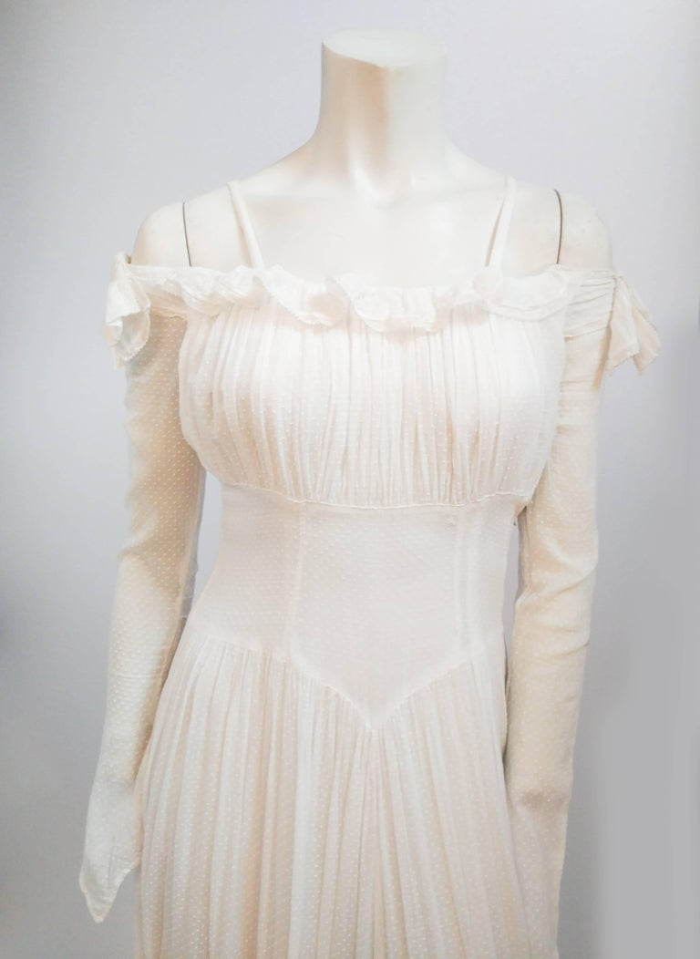 1940s White Swiss Dot Wedding Dress. Peekaboo shoulders adorned with small ruffle trim. Long sleeves come to a point at hand. Gathered bust and basque waist. Full length train at back. 