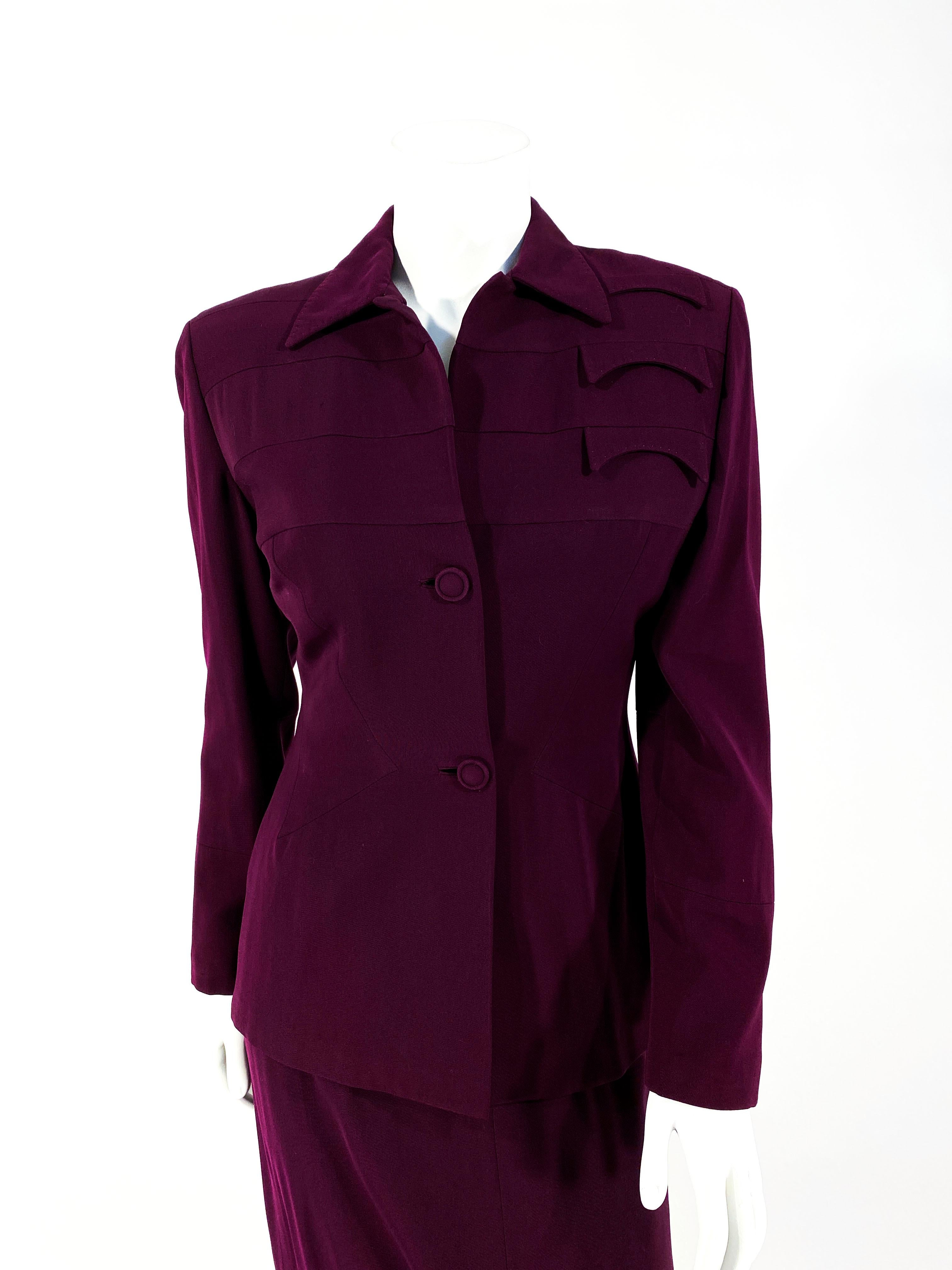 1940s wine colored wool gaberdine suit with bands of reverse material below the shoulders. The faux pockets are hand stitched decorative along the left shoulder. The cuffs are decorated with matching panels that complement the shoulder of the