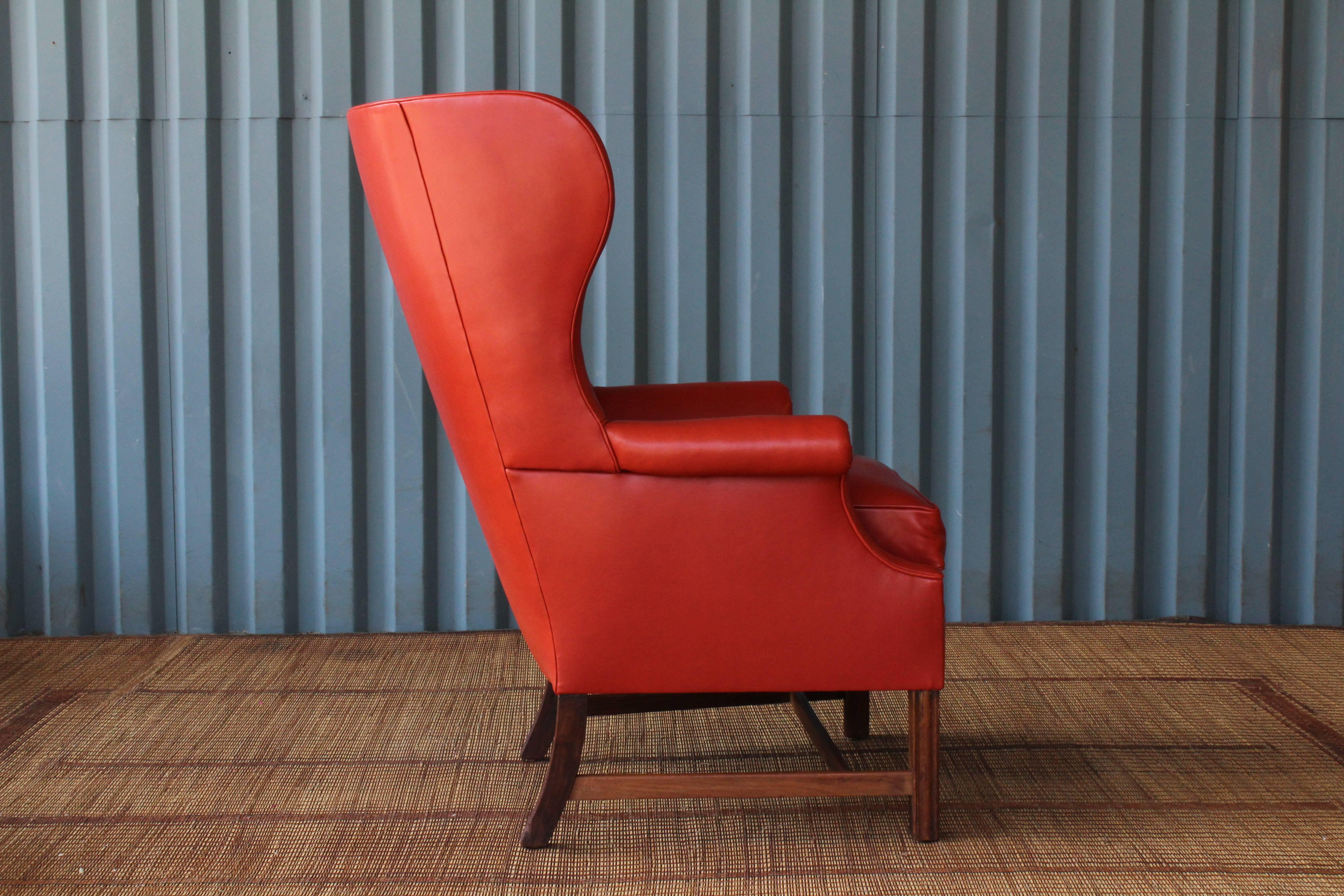 1940s wingback armchair featuring new orange leather upholstery. Walnut base shows signs of age appropriate wear. Leather is soft and in excellent condition.