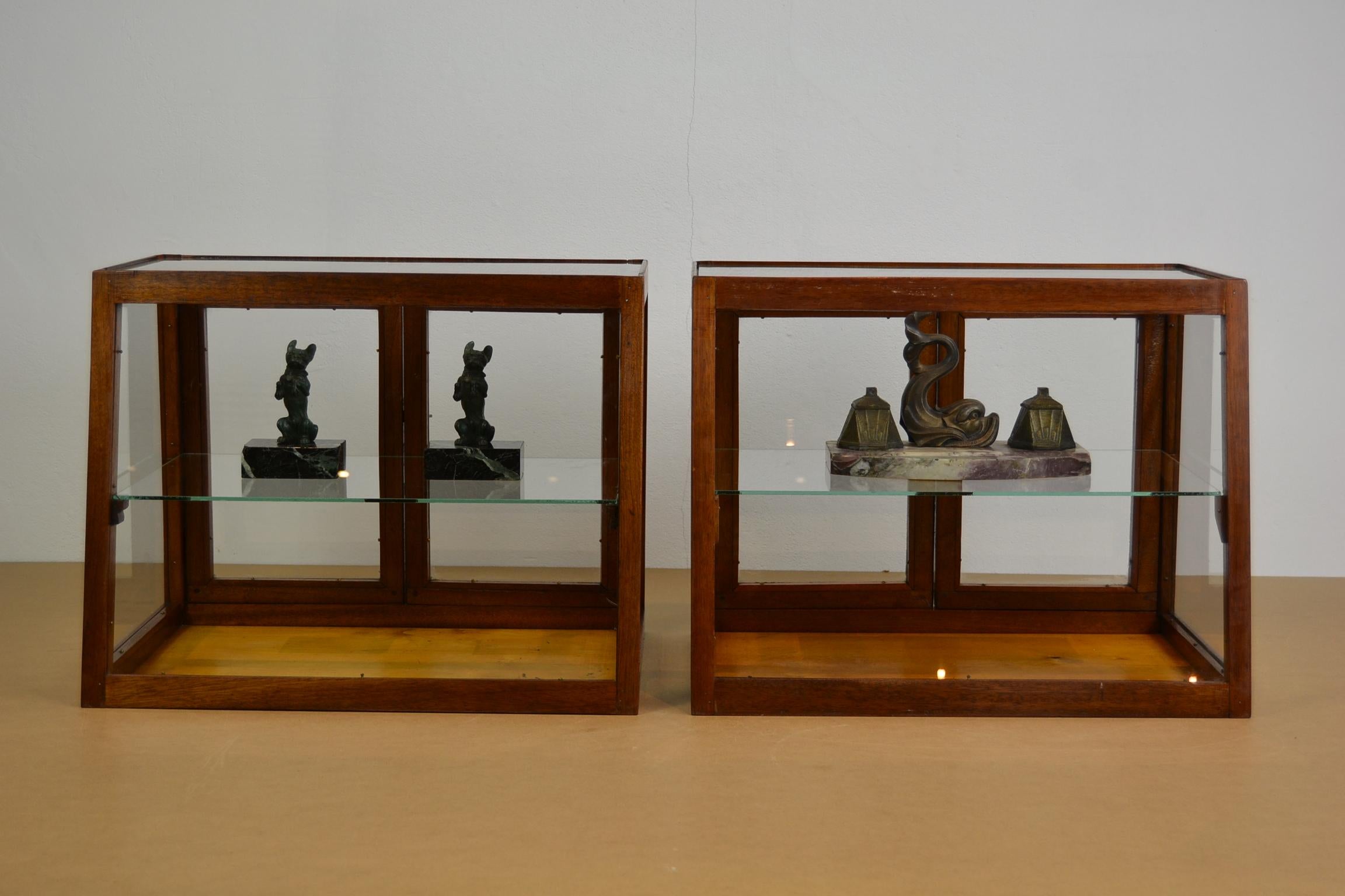 Available, 2 x Art Deco counter -top display showcases from the 1940s.
Wooden vitrines with a slanted front, a glass barr and 2 doors at the back with a metal bolt.
You can see from every angle what's displayed as you have glass all around, even