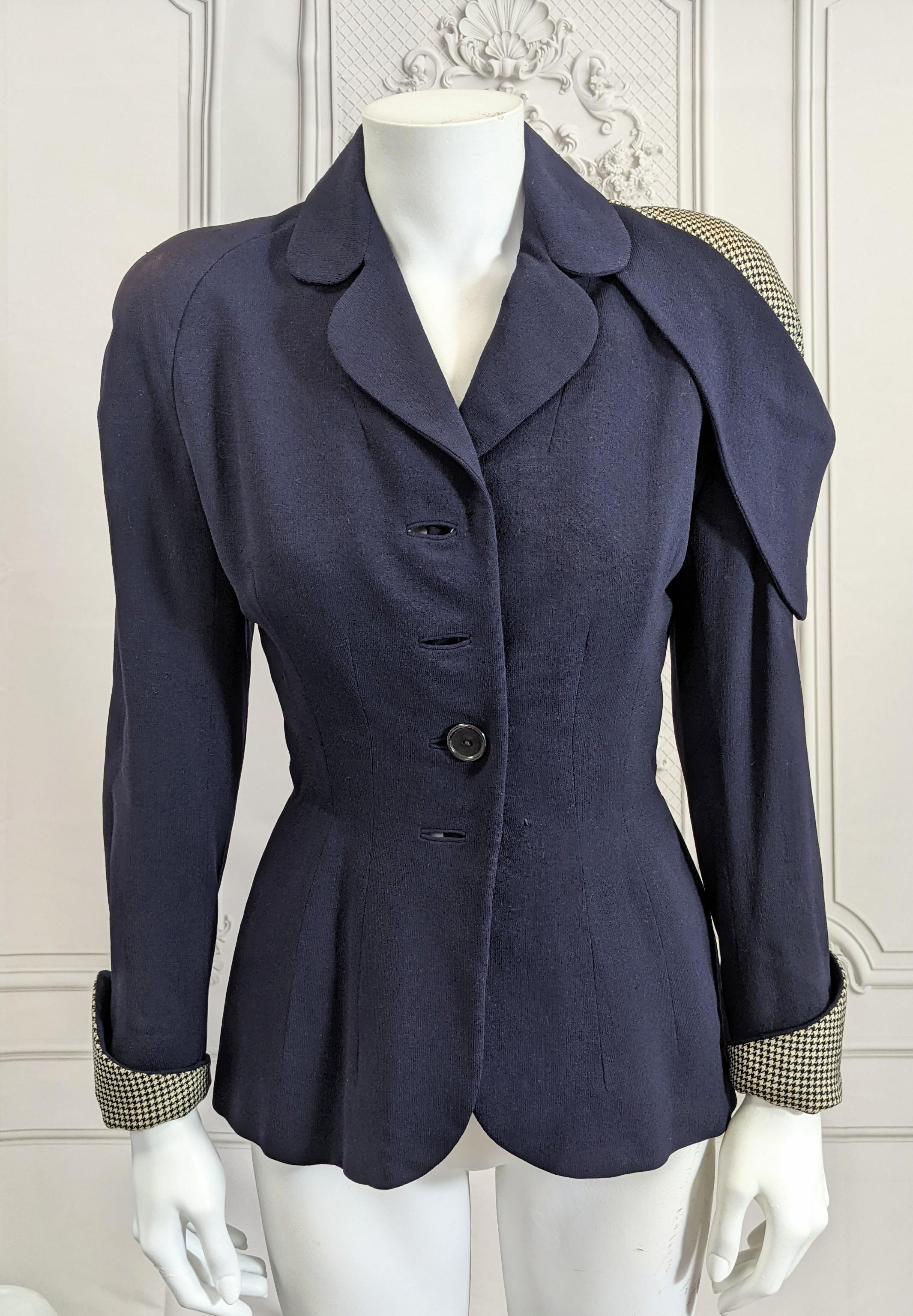 Unusual Wool Cold Shoulder Houndstooth Jacket from the 1940's. Navy wool worsted with a strong exposed shoulder which is covered in houndstooth wool with matching cuffs. Tiny waist with padded hips and self buttons. Small size. Mannequin is size