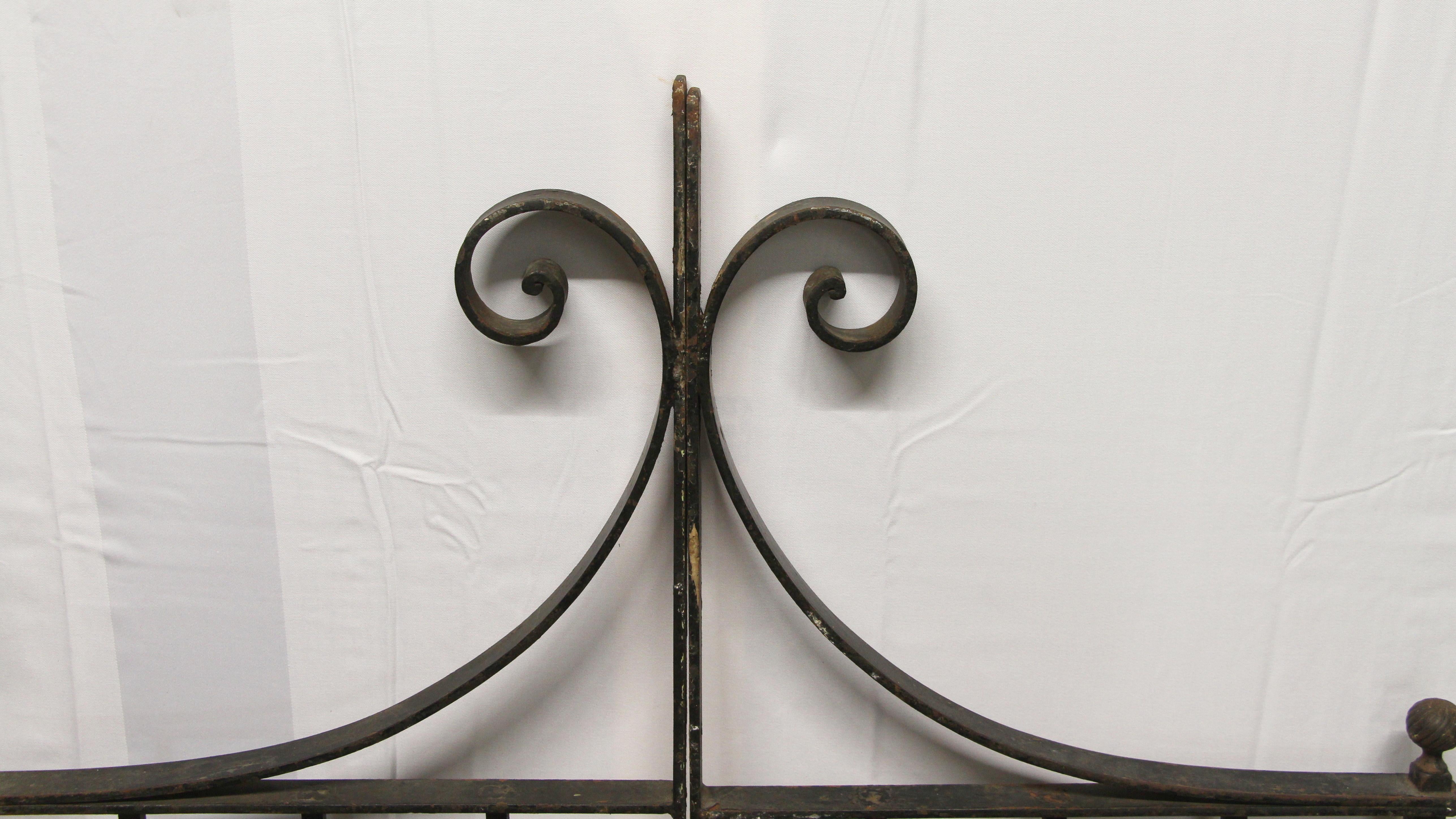 Simple forged iron double garden gate set with an old black finish. The surface is worn and will need refinishing. Center scroll design, circa 1940. Sold as a pair. This can be viewed at our Scranton, Pennsylvania location. Please inquire for the