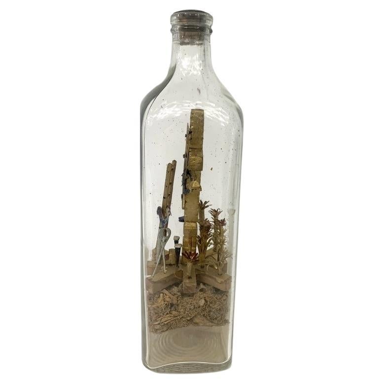 Une bouteille de patience chrétienne symbolique avec une croix flanquée de cloches miniatures, l'avant avec une échelle, des outils, des plantes et un coq. Le flacon contient une étiquette en papier signée, datée du 3 octobre 1941, Arequito avec