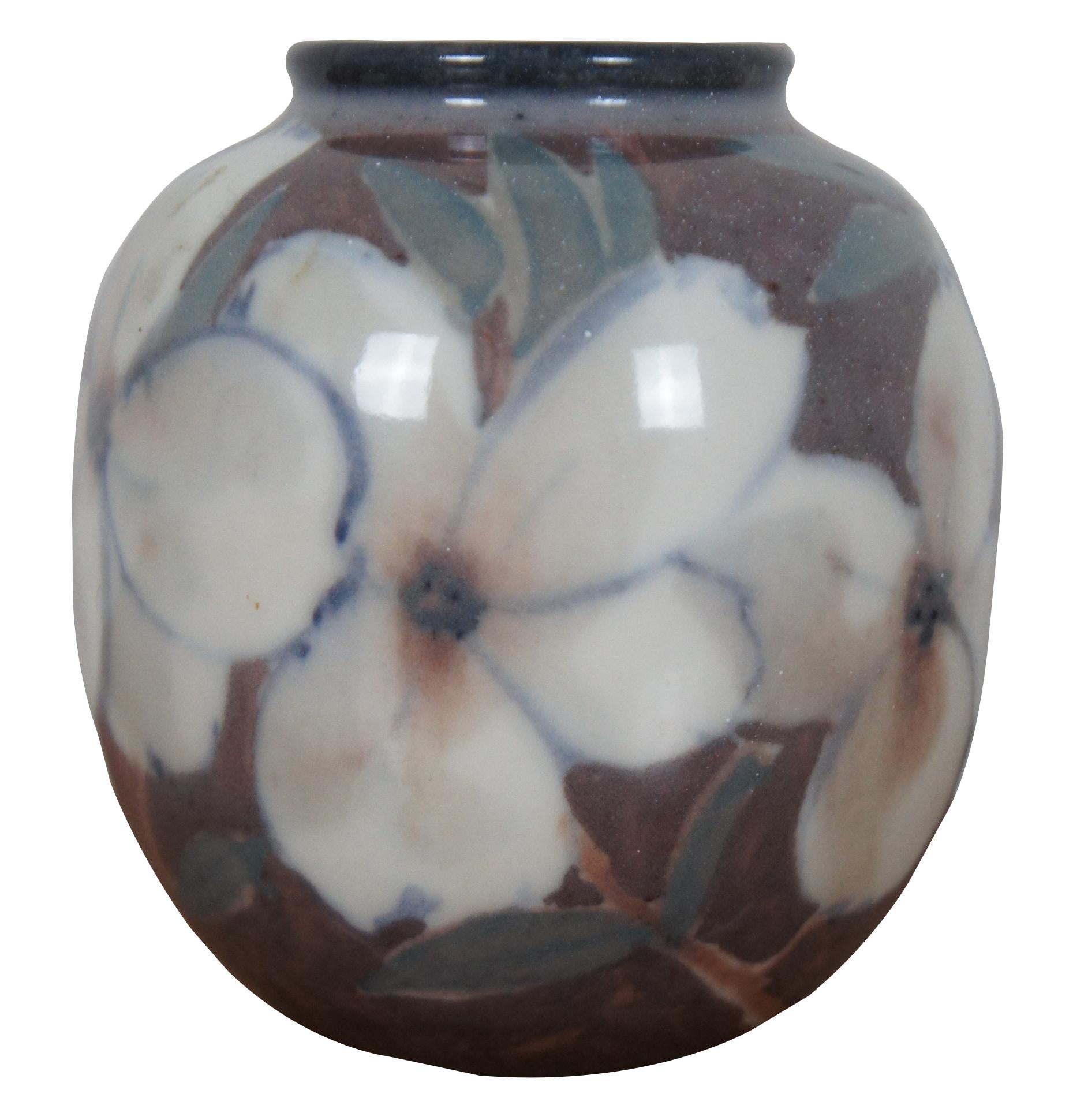 Vase ancien de 1944 en porcelaine de Rookwood Pottery avec un design floral de Jens Jensen représentant des fleurs blanches de cornouiller ou de magnolia sur un fond marron tacheté.

 