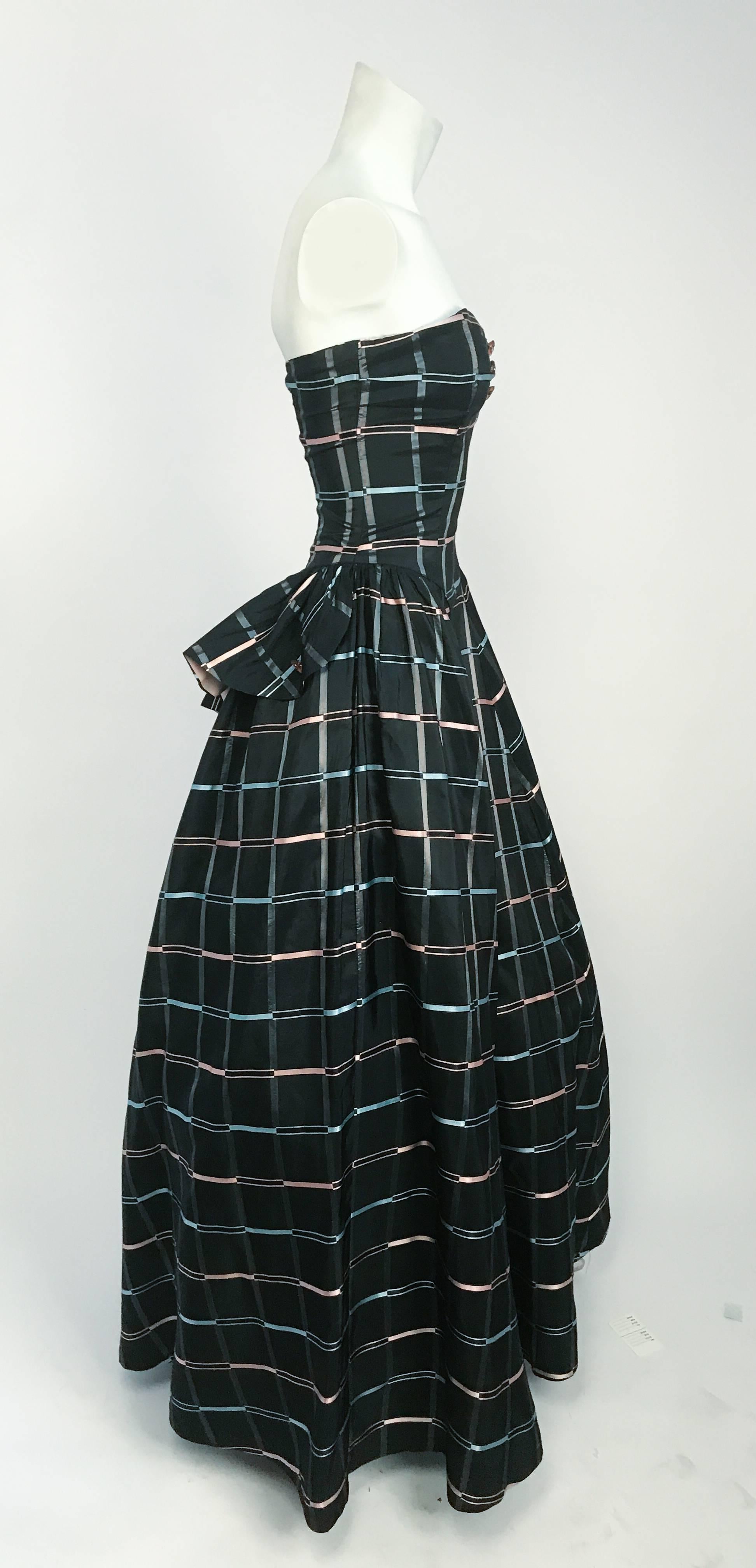 1945 Strapless Plaid Evening Dress. Black plaid dress with pink buttons with clear rhinestone center and peplum side accents. Garment shot over a petticoat on.
