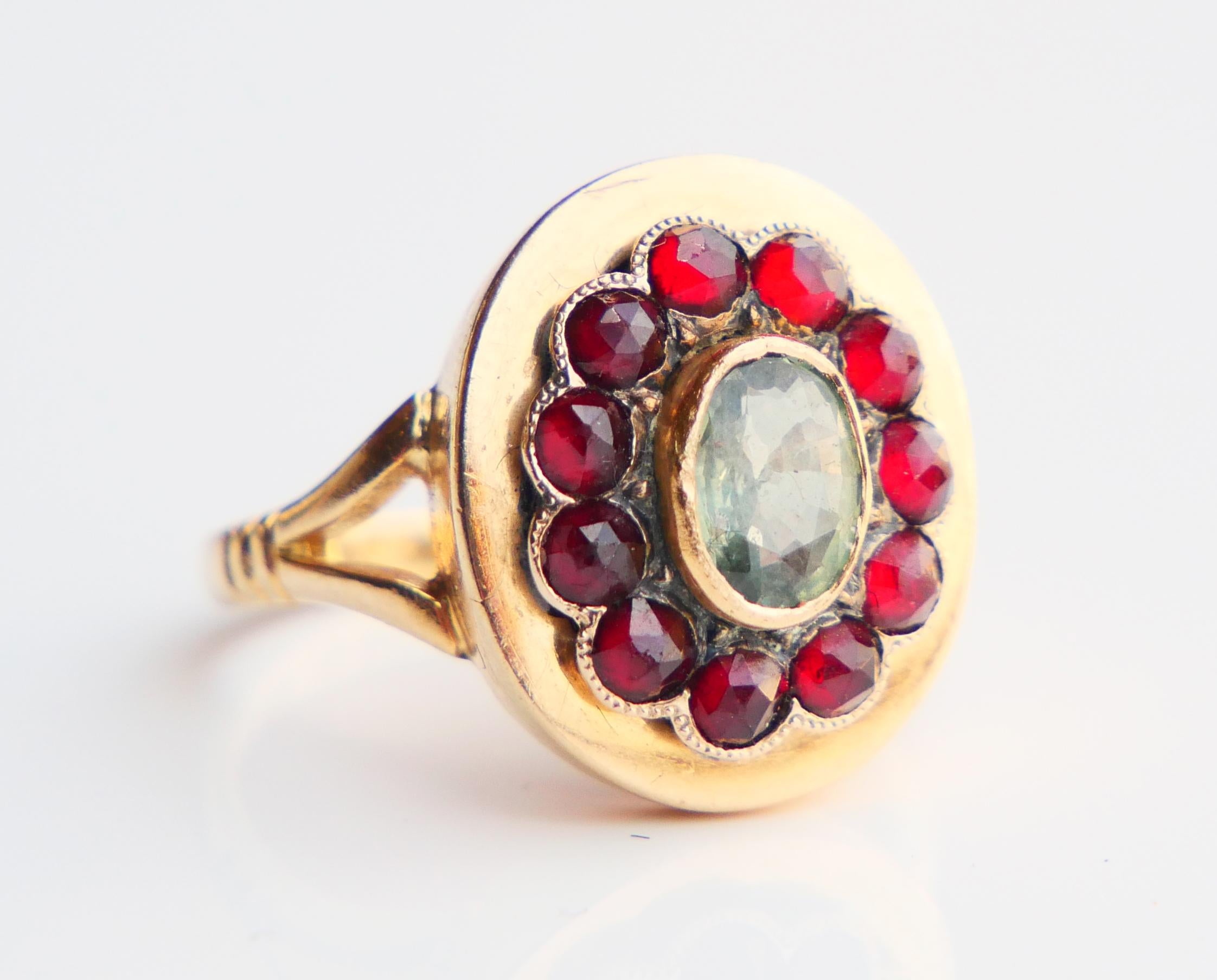 Poison Ring in solid 18K Yellow Gold with Flower crown decorated with natural Green Sapphire 6.5 mm x 5 mm / ca. 1ct  and eleven Bohemian Red Garnets cut rose Ø 2.75 mm / ca. 0.17 ct each. Behind Sapphire there is a hidden air- tight compartment 12