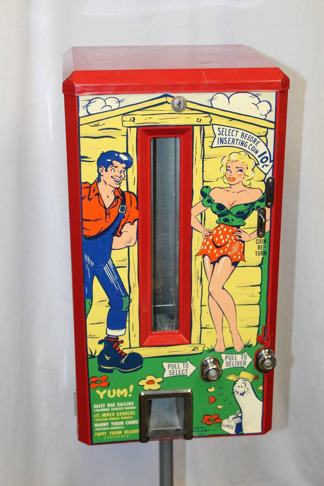 California Dispenser Co. Mechanical steel candy machine with long glass window at front and dime slot. Three sides have illustrations of Dogpatch characters including - Li'l Abner, Daisy Mae, Mammy Yokum, Pappy Yokum, Shmoo. Machine used to offer