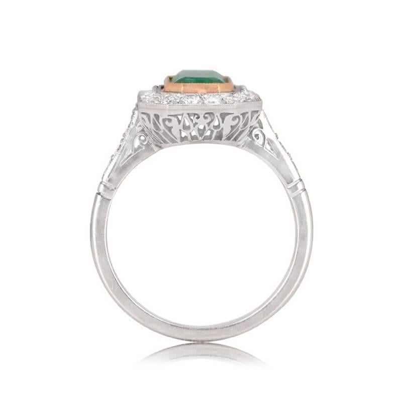 A captivating platinum ring with an elongated design, showcasing a center emerald-cut natural emerald set in an 18k yellow gold bezel. The center gemstone is encircled by a row of old European cut diamonds. Hand-crafted in platinum, this ring boasts