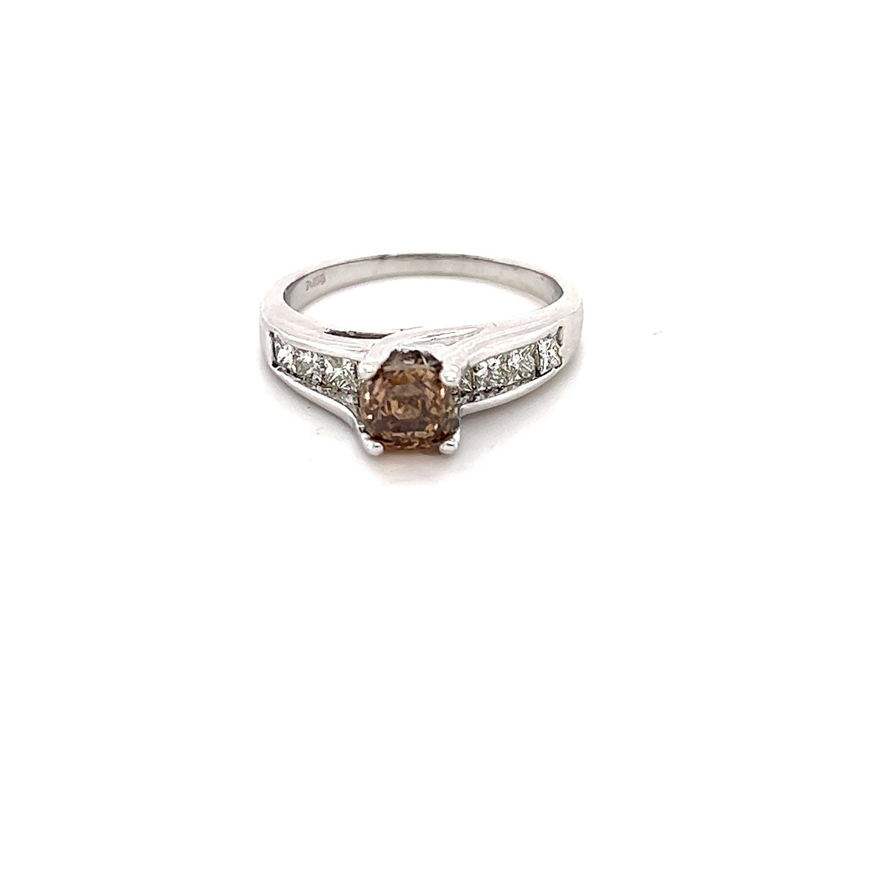 This ring has a Asscher Cut Brown Diamond that weighs 1.10 Carats with a VS clarity. It has 9 Princess Cut Diamonds that weigh 0.85 carats. The Clarity and Color of the Diamonds are VS-F. The total carat weight of the ring is 1.95 Carats. 

Crafted