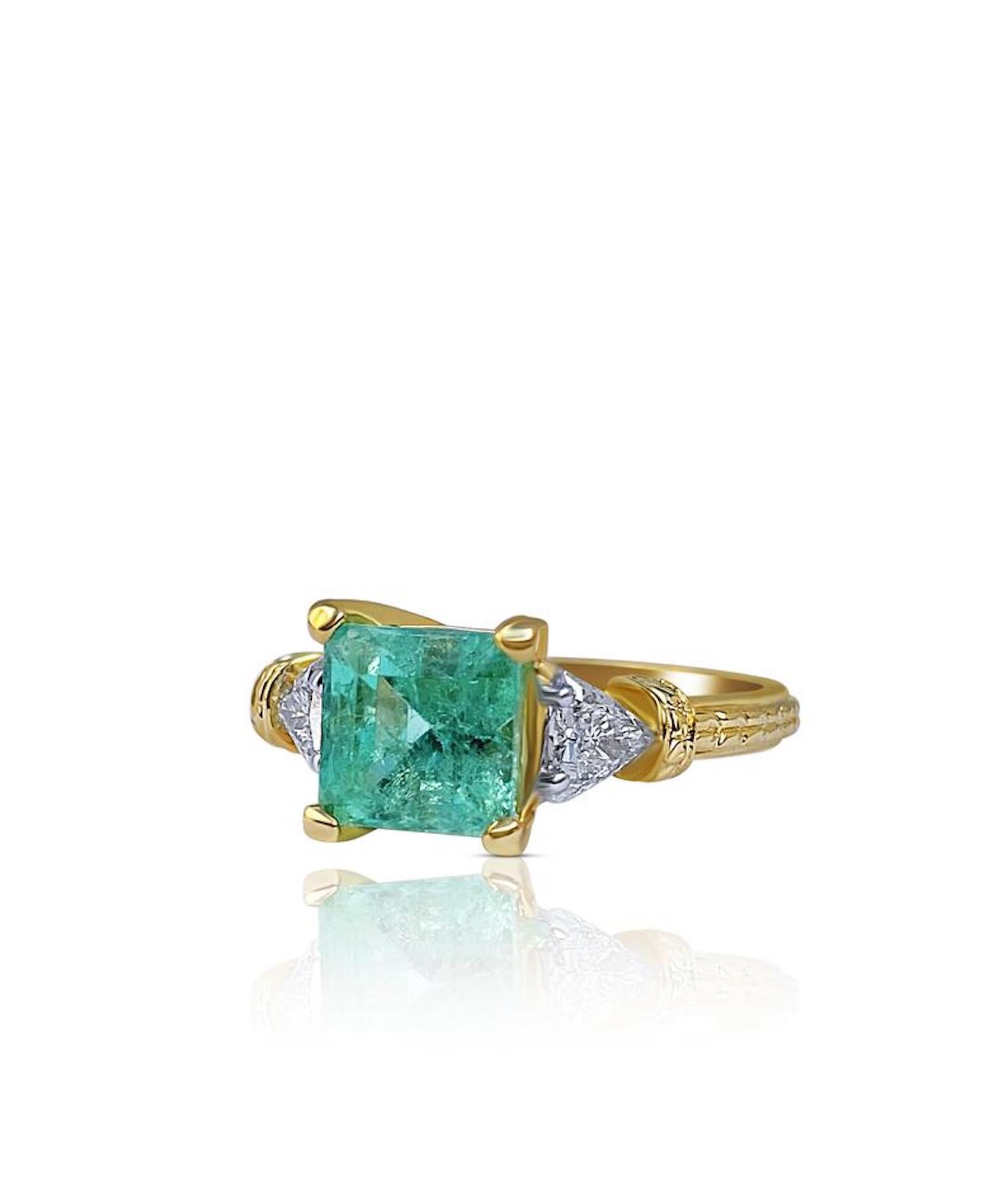 Centering a 1.95 carat Colombian Emerald, flanked by two 0.20ct Trilliant-Cut Diamonds, and set in 18K Yellow Gold, this beautiful Vintage Emerald Engagement Ring is the perfect fit for those searching for a unique, unconventional engagement