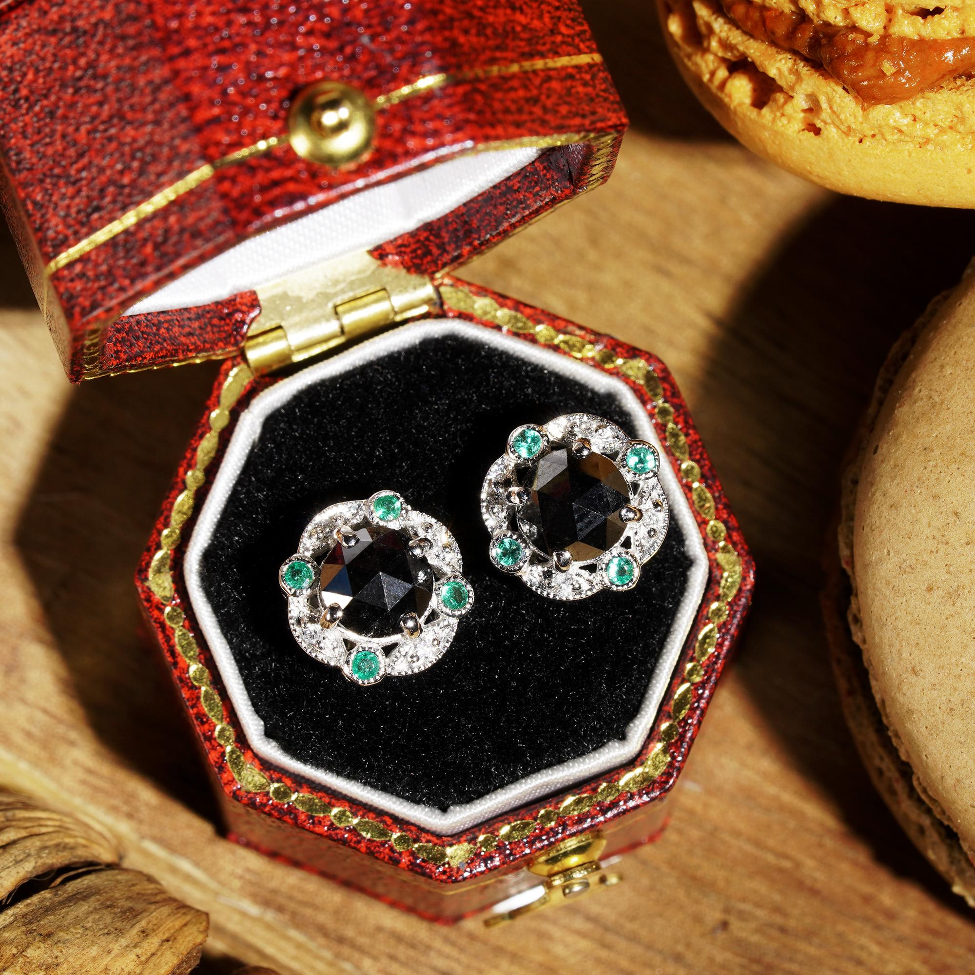 Black diamonds are surrounded by glittering halos of sixteen white diamonds and four emeralds on each piece. Glamorous and elegant, these stud are perfect to wear day and night. 

Earrings Information
Style: Art Deco
Metal: 14K White Gold
Width: 10