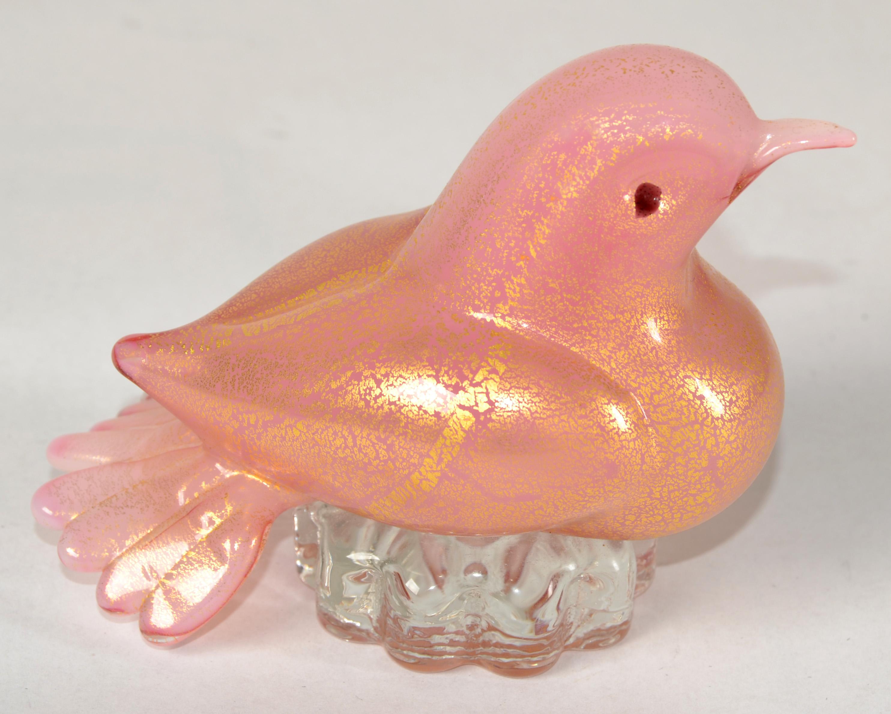 Uccello, scultura, statuetta o fermacarte in vetro soffiato rosa e oro di Murano d'epoca su base trasparente.  
Documentato al designer Alfredo Barbini, intorno agli anni 1950-60. 
L'uccello ha un colore rosa ed è ricoperto di foglie d'oro su tutto