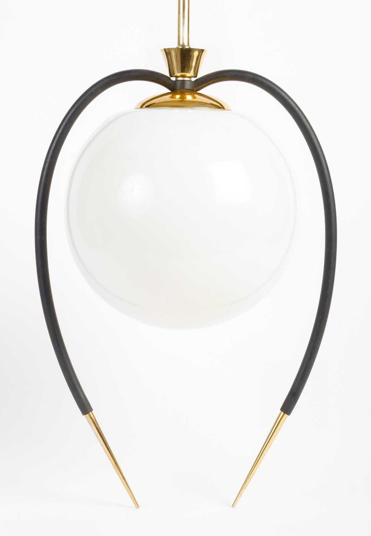 Composed of a central rod acting as a gilded brass light arm, dressed on the side with a round opalescent globe framed by two black wrought-iron rods curved downwards and embellished at their ends with fine gilded brass spikes held on the luminaire