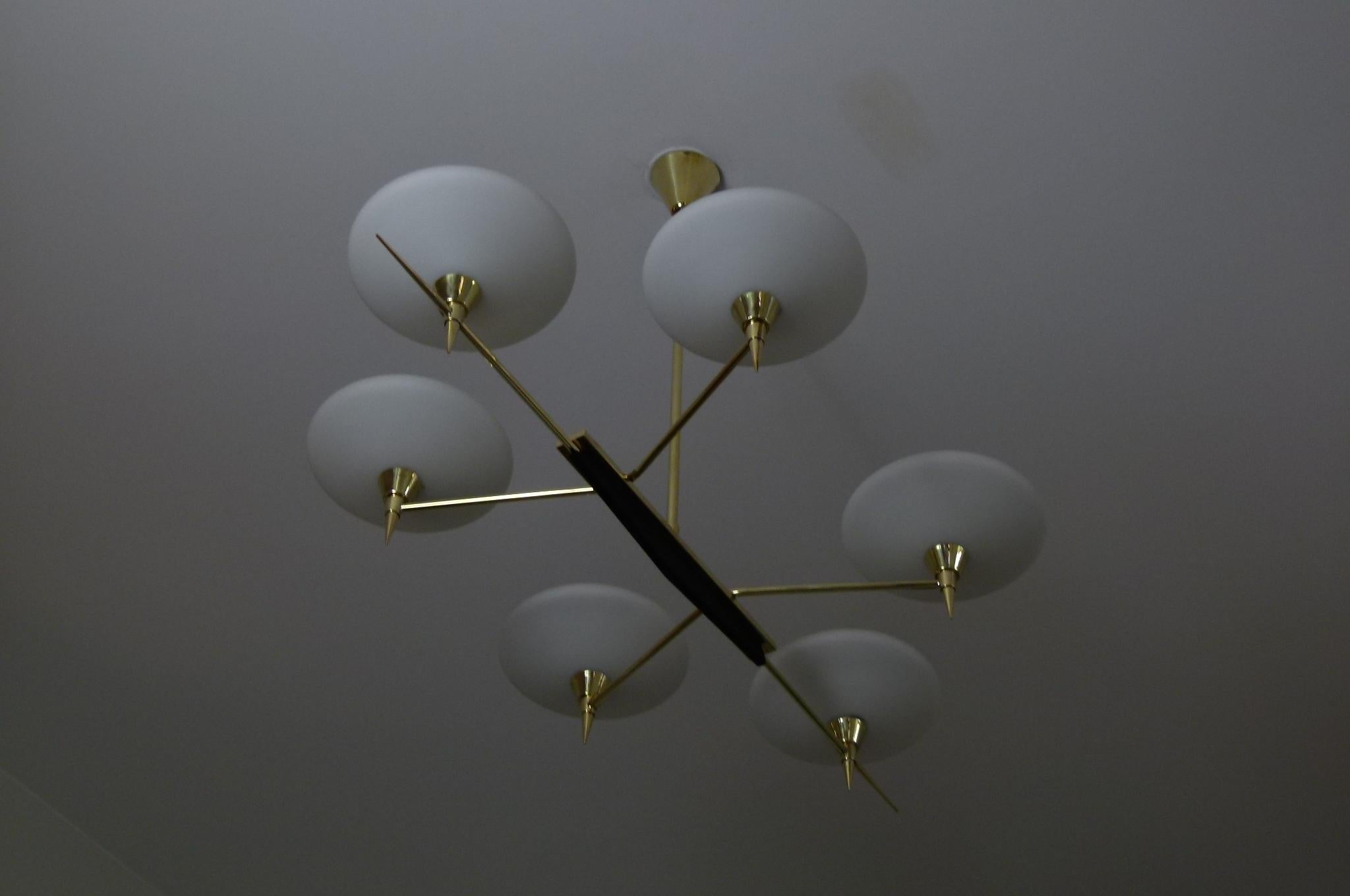 Brass chandelier, composed of 6 arms of light, brass,
on which opal glass shades are arranged,
connected in them, by a rectangular plate solid brass.
a black lacquered metal deco is placed below the base.

This chandelier has been fully