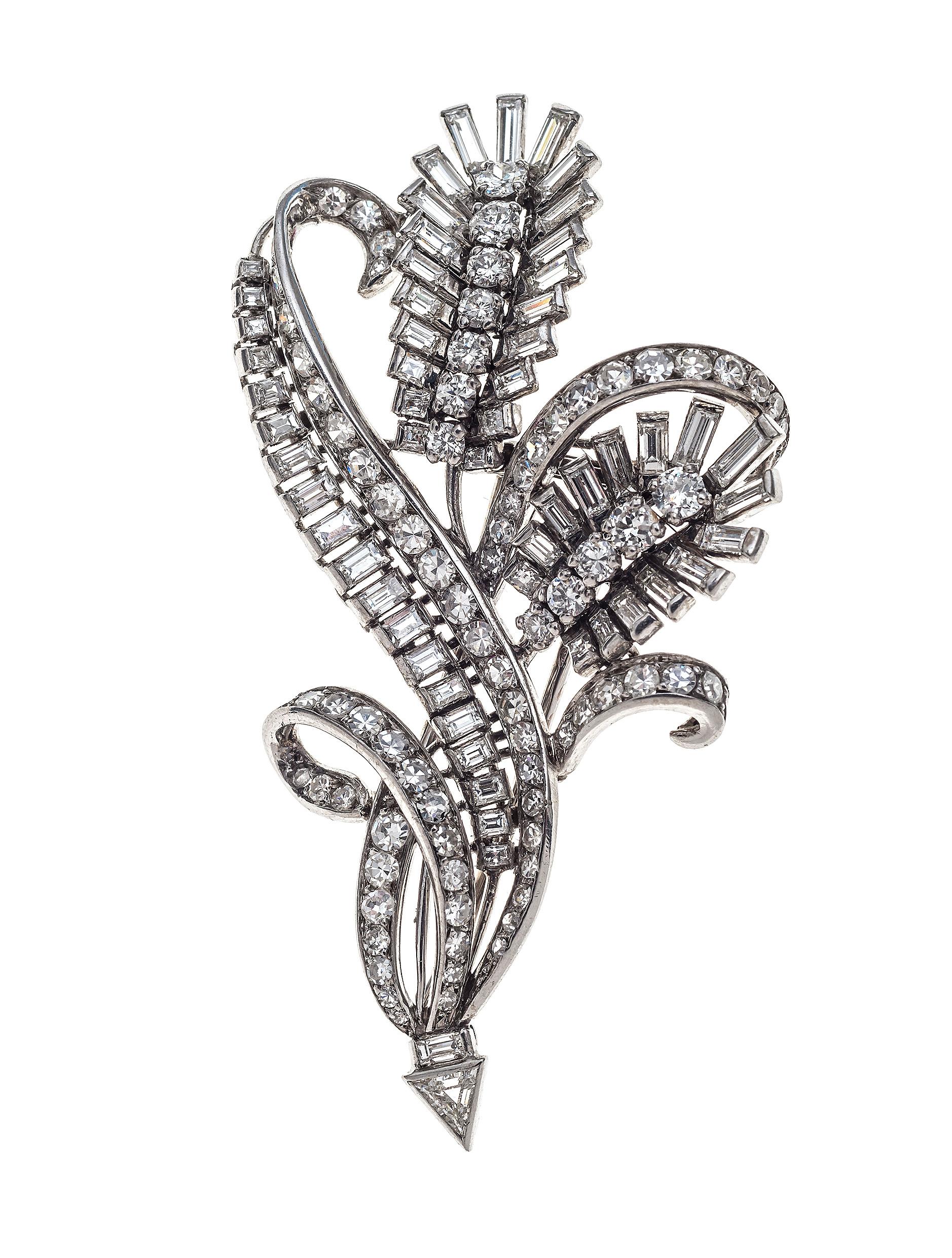 The dress clip consists of two flowers and stylised leaves set with fifty-five baguette cut diamonds, one triangular diamond, and sixty round diamonds set in platinum. Each clip has thirty-one baguettes and twenty-seven round diamonds in brilliant
