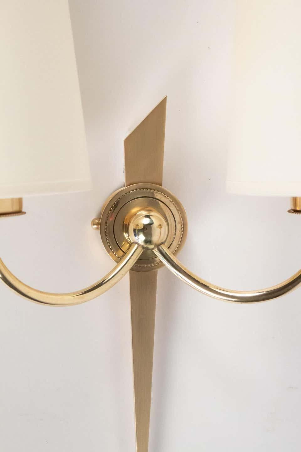 Elegant pair of wall lights from Maison Arlus in gilded bronze and brass.
Composed of a central arm representing a stylized arrow
in matt gilded bronze.
Two curved arms in gilded brass on either side of the wall light meet at the level of the