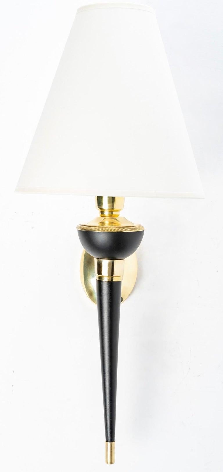 Composed of a wall support of oval shape in gilded brass on which is posed an arm of light in the shape of point in blackened wood heightened on the low part of gilded brass and on the high part retained with the wall support by a ring in gilded