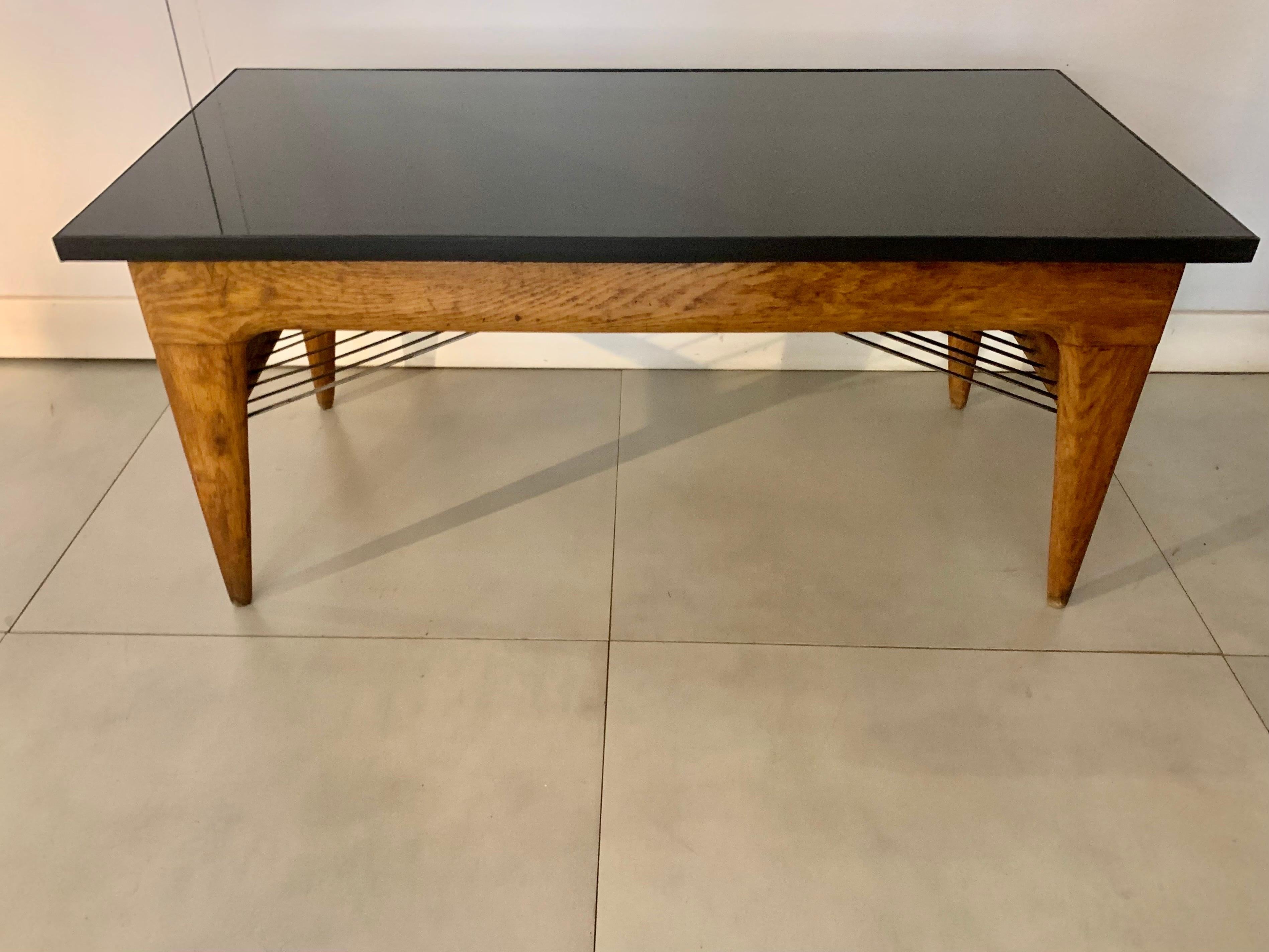 Coffee table in French oak, from the 1950s, with black lacquered metal and black glass top,
In the lower part they have some black rods that are used to support press, or papers, the legs in the shape of a stipe.