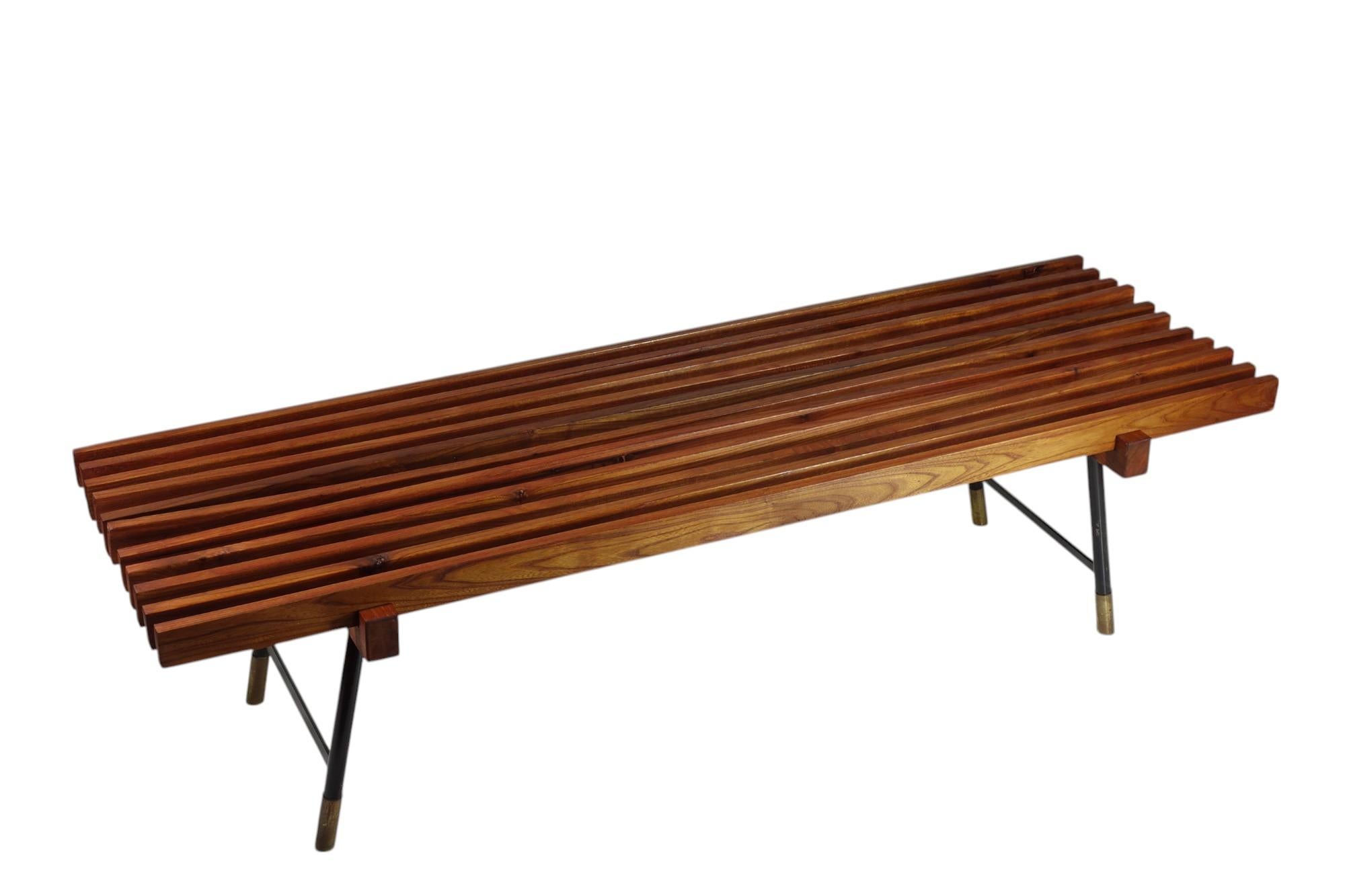 Italian Teak Bench
1950

Solid wood slatted bench
Black laquered iron legs with brass details

One bend wood slat (shown in the picture)
Very good condiction
Original 1950