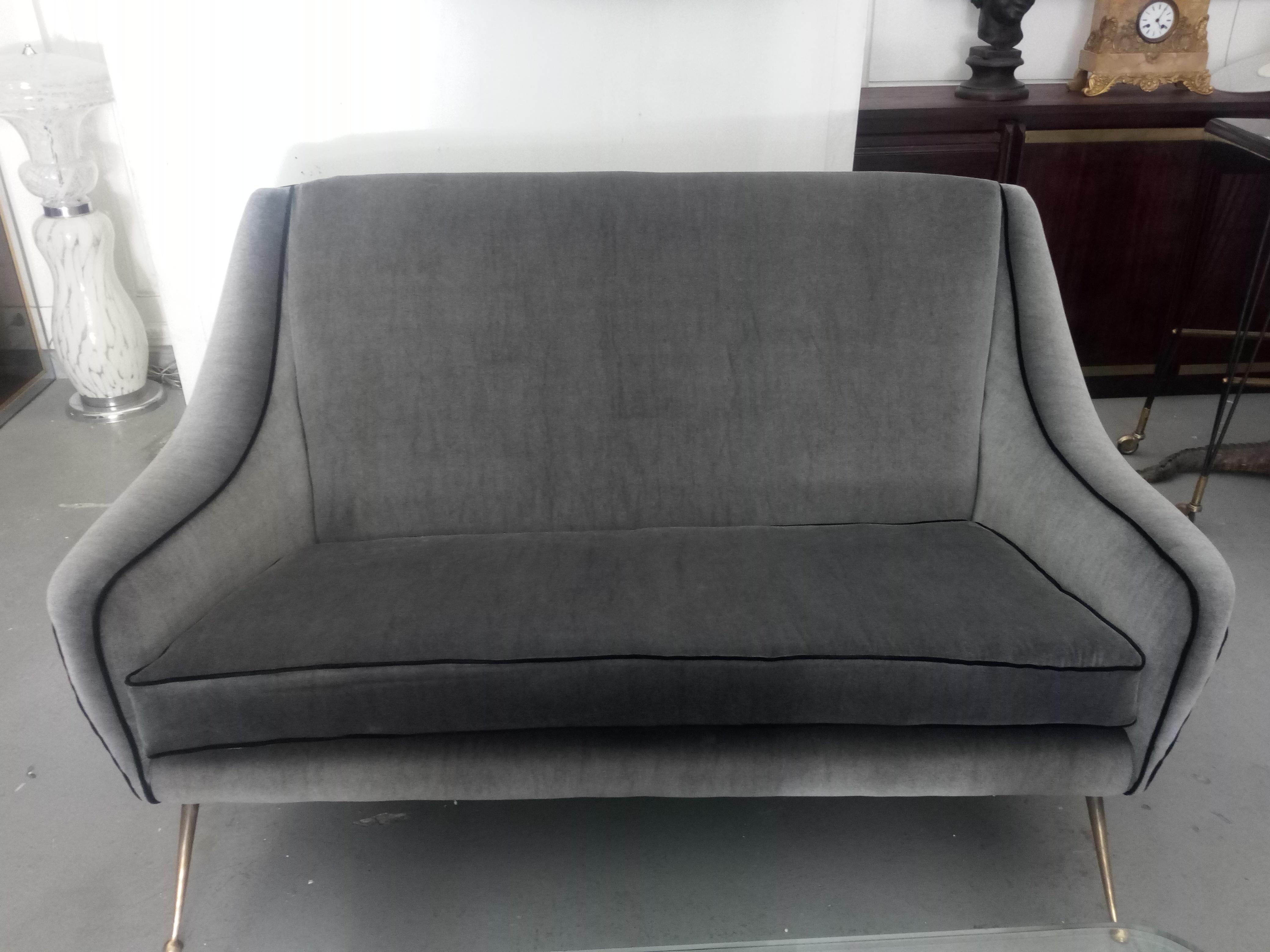 1950, elegant Italian sofa with brass feet, upholstered in gray fabric with black borders.
