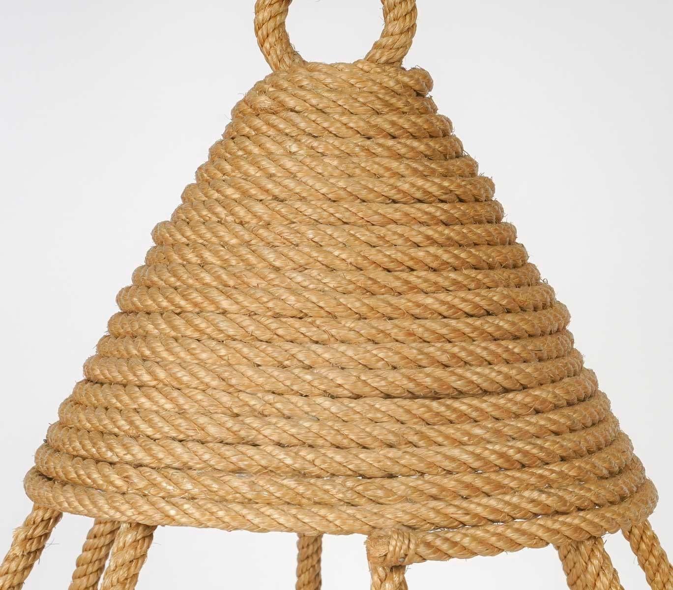 Composé d'une tige de corde centrale sur laquelle repose une lanterne coiffée d'un chapeau de corde pointu enroulé au sommet et décoré à la base de tiges de corde courbes placées verticalement, formant une cage autour de la lanterne.
En bas, les