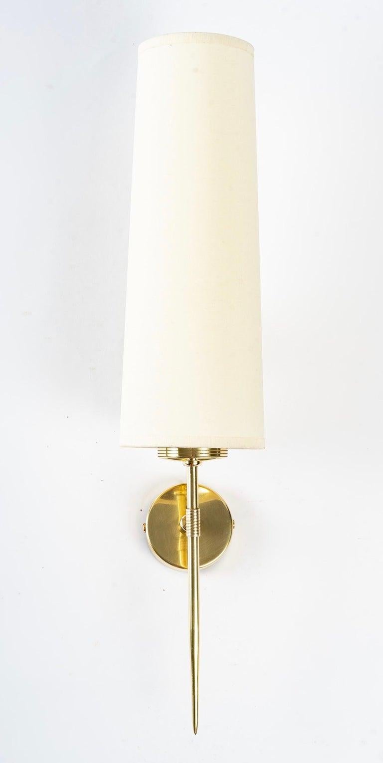 1950 Large pair of sconces from the House of Arlus in gilded brass
Elegant and minimalist wall sconces in gilded brass. 

The sconces consist of a round back plate on which is positioned a thin rod ending in a point at the end and slightly