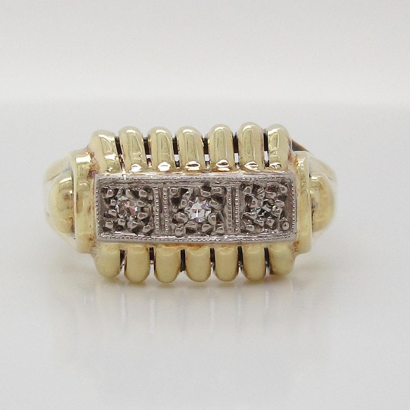 This is a beautiful mid-century ring in 14k yellow gold with a unique, architectural twist on a three-stone diamond ring! This ring takes the classic three-stone layout, which is timeless in its symbolism of the past, present, and future, and adds a