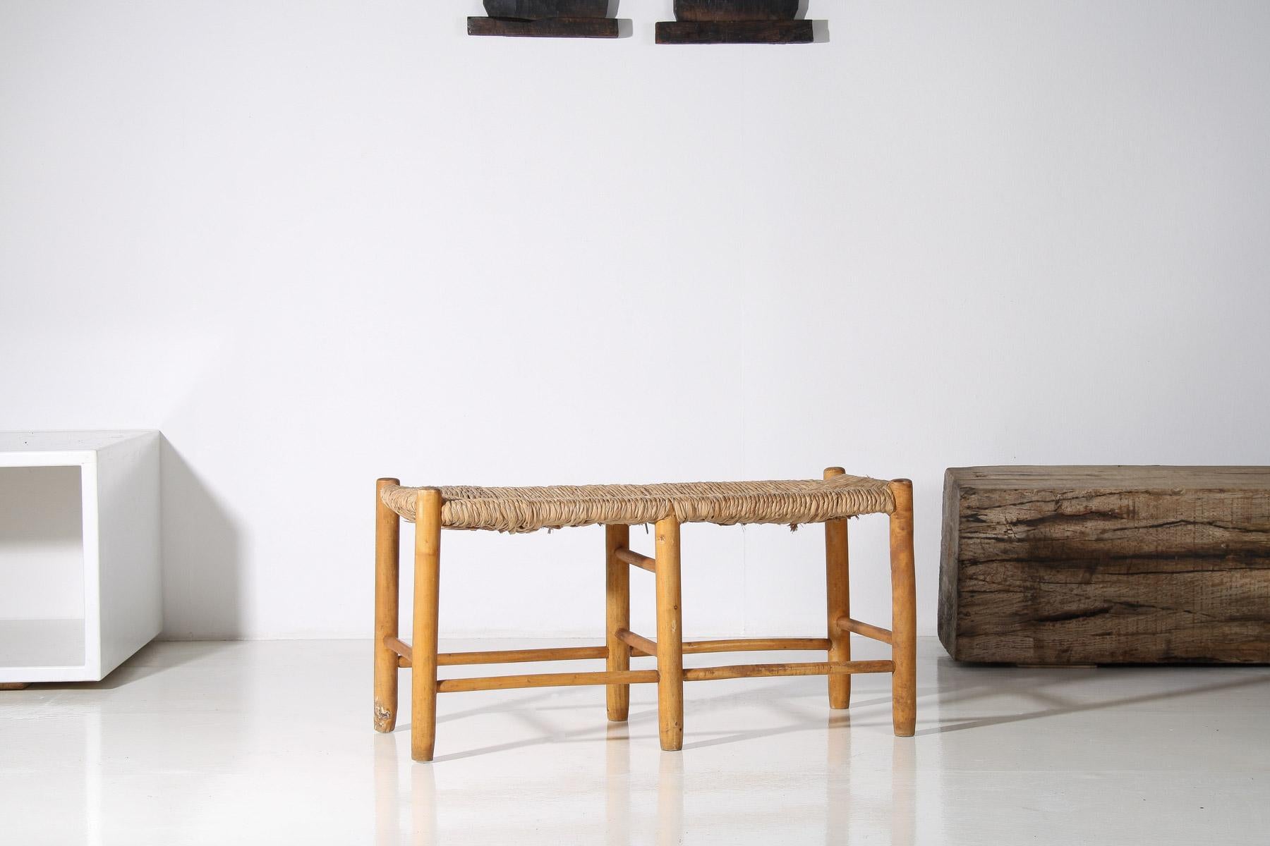 A characterful 1950s French straw rush seated bench, inspired by the iconic designs of Charlotte Perriand. Crafted from solid pine, this charming piece is ideal as a small occasional bench, accommodates two people, making it a versatile addition to