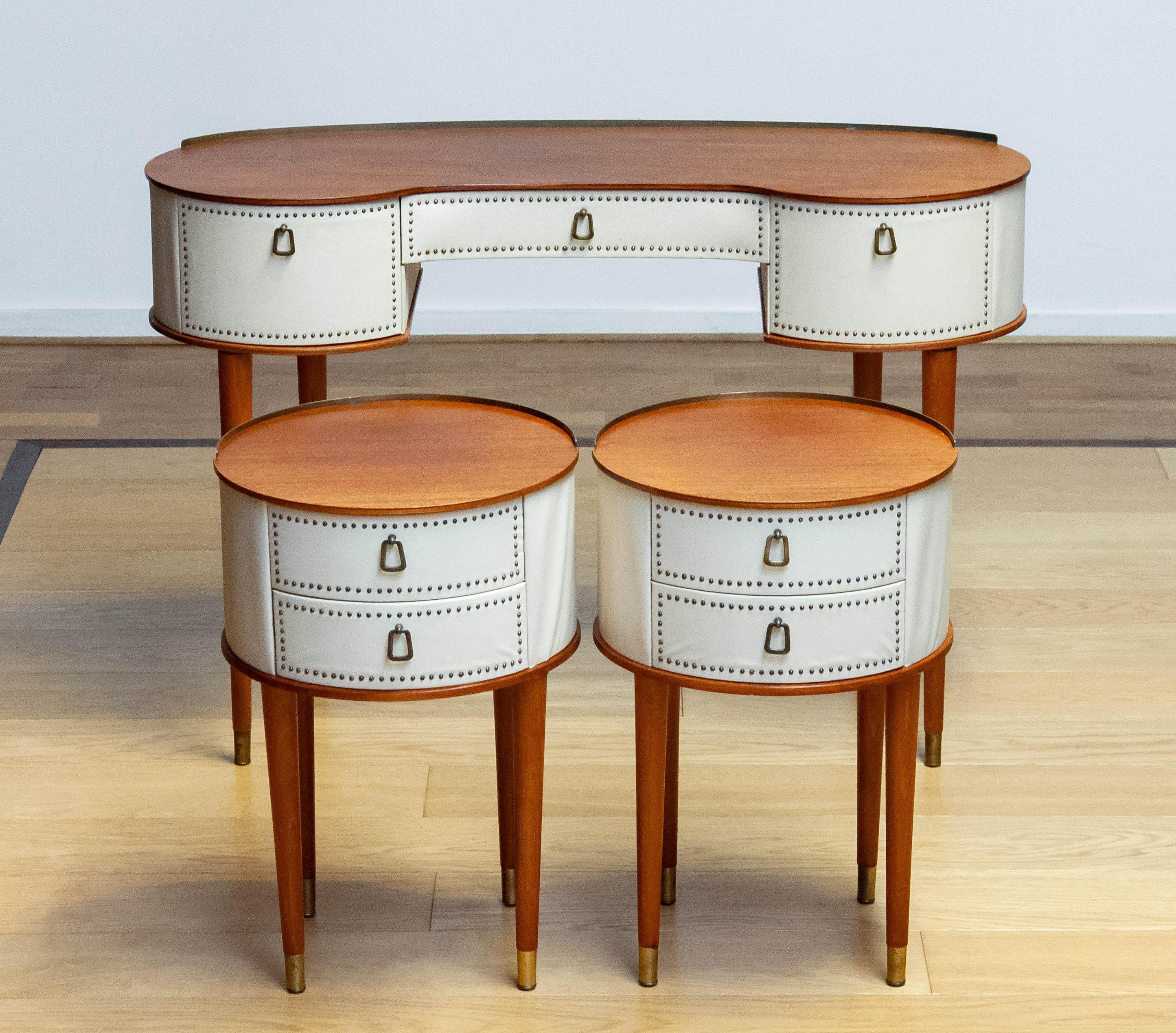 Beautiful and absolutely rare matching set of a pair night stands / bedside tables and a Vanity / dressing table all three designed by Halvdan Pettersson for Tibro in Sweden from the 1950s.
Covered with beige faux leather. Both nightstands / bedside