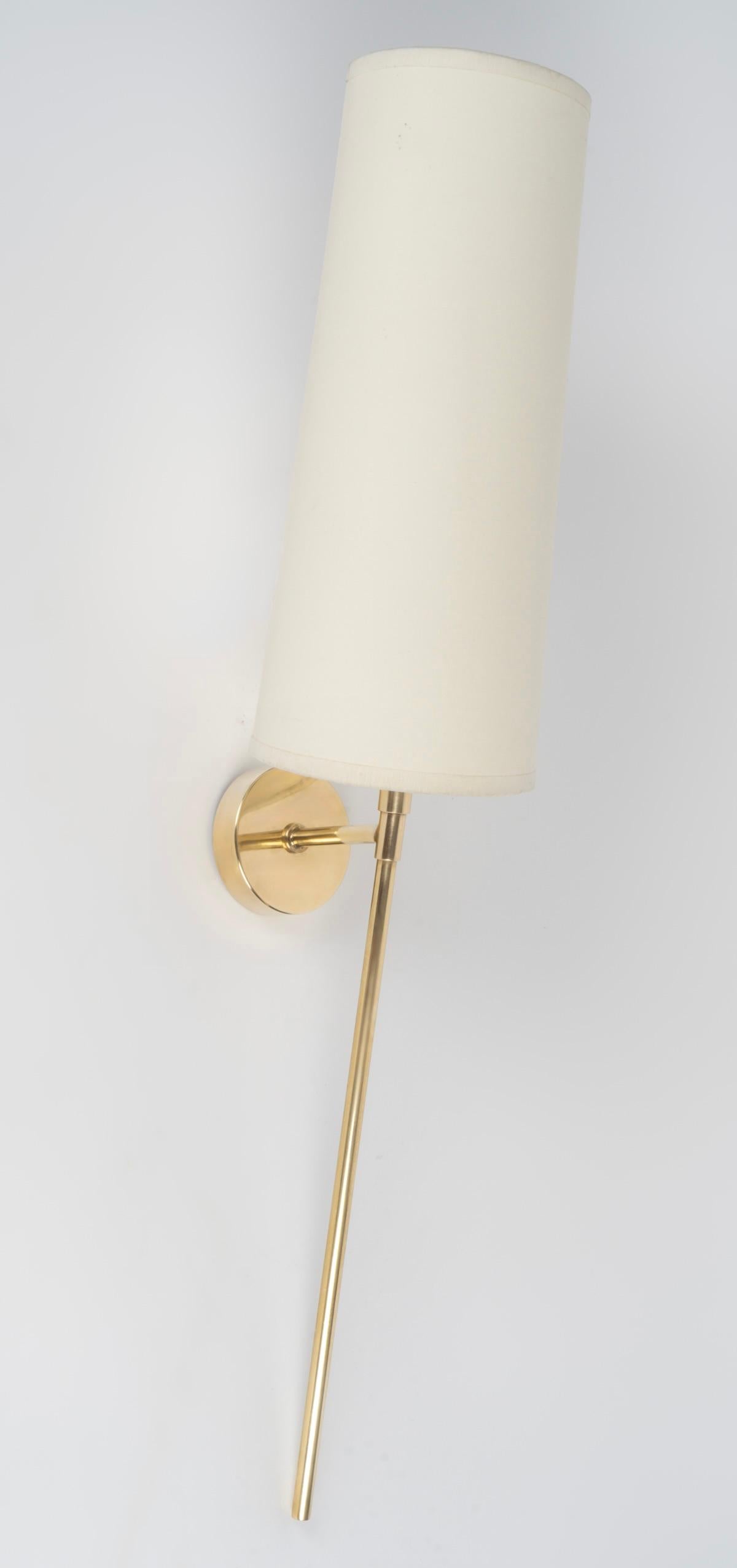 Composed of a round wall support on which rests a luminous arm formed by a long rod, all in gilded brass. 
A trapezoidal shade in off-white cotton, identical to the original, covers the lamp.

1 arm of light.